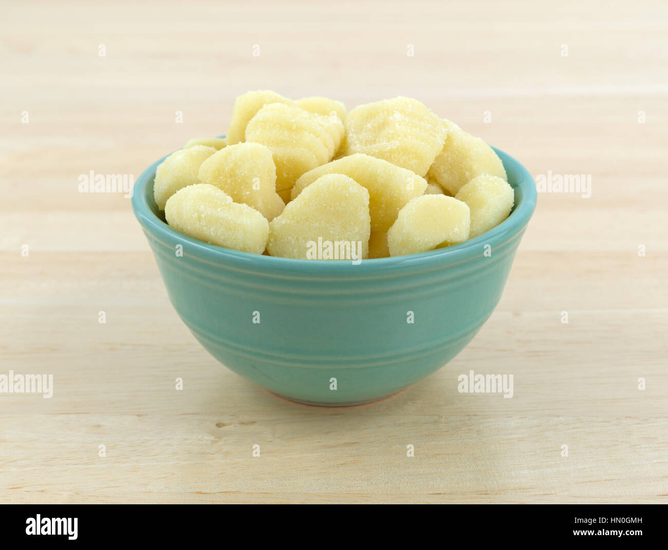 Plain gnocchi di patate in una ciotola verde sulla cima di un tavolo di legno. Foto Stock