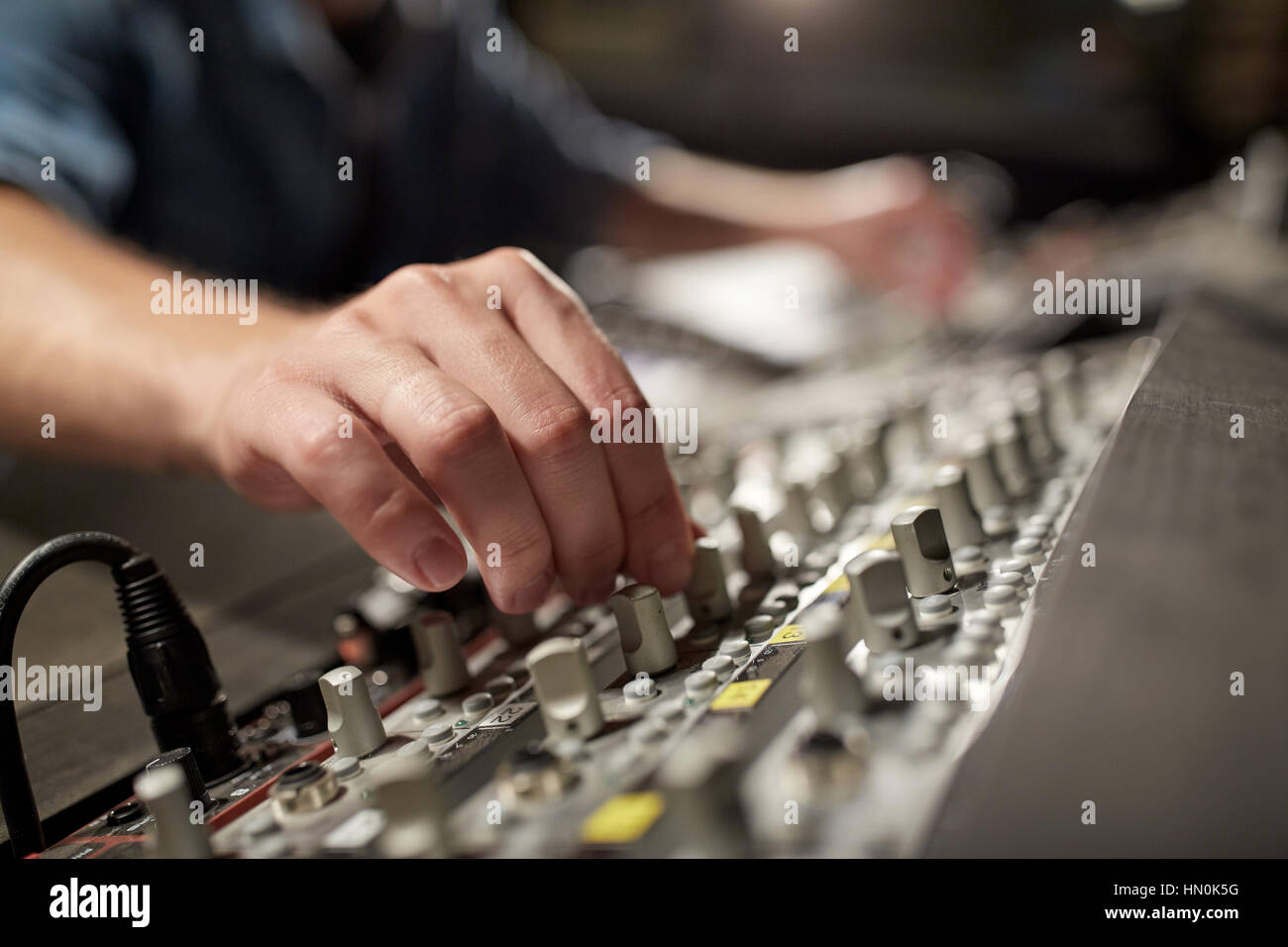 Uomo che utilizza la console di miscelazione in music studio di registrazione Foto Stock