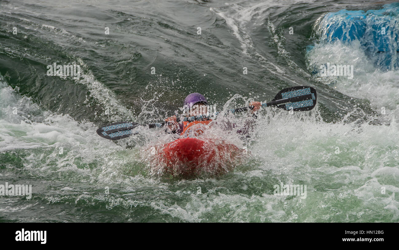 Un kayaker navigazione attraverso alcuni molto ruvida rapids su un uomo bianco fatto il corso di acqua Foto Stock