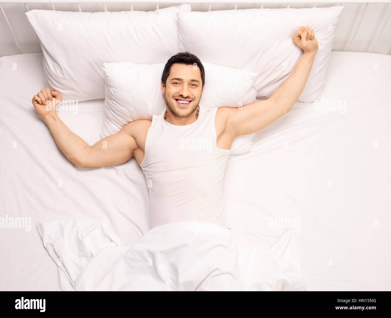 Ragazzo bello svegliarsi e stretching nel letto Foto Stock