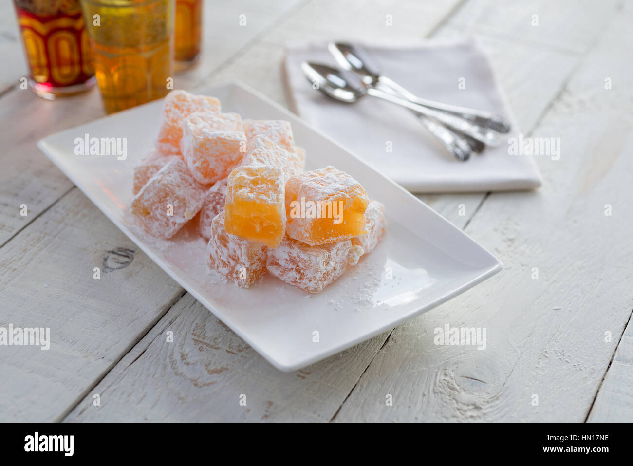 Una piastra di colore arancione in casa e mandorla delizie Turche. Tavolo bianco sullo sfondo. Foto Stock