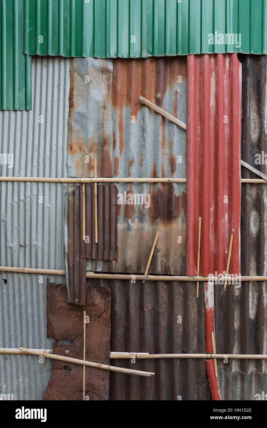 Una parete composta da fogli dispari di ferro corrugato colorato/colorato rugoso. Kompong Cham, Cambogia Foto Stock
