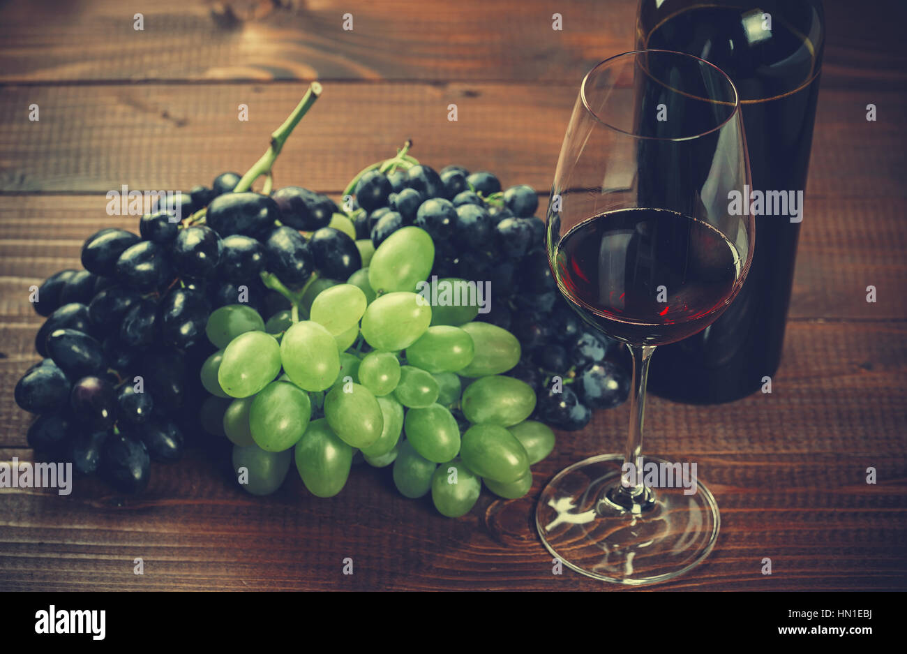 Bottiglia e bicchiere di vino rosso e Uva su sfondo di legno Foto Stock