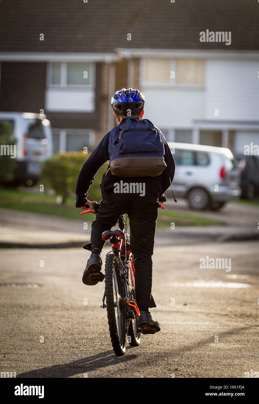 Una vista posteriore di un ragazzo a scuola in bicicletta a scuola Foto Stock