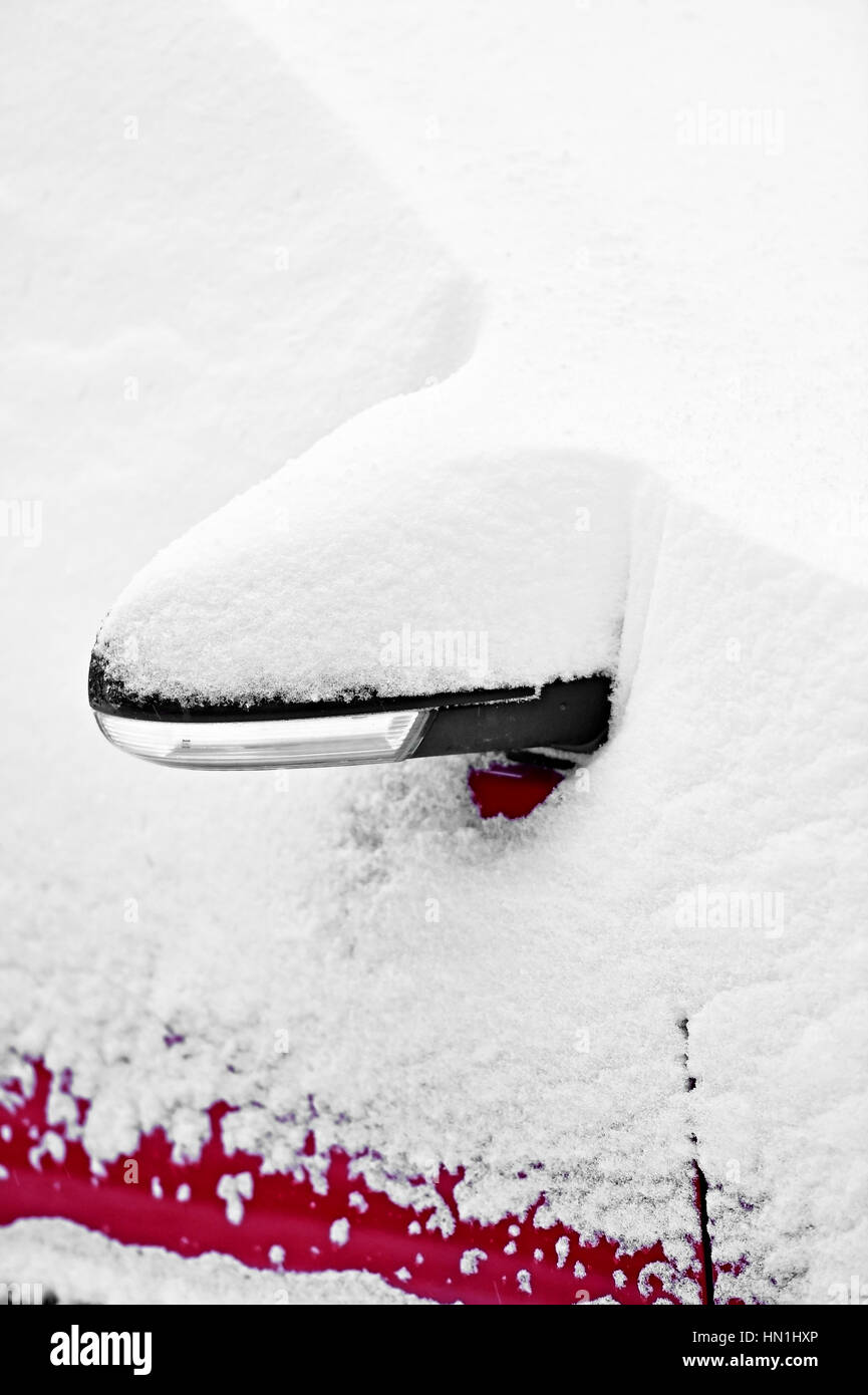 Lo specchietto laterale di una coperta di neve auto durante la nevicata Foto Stock