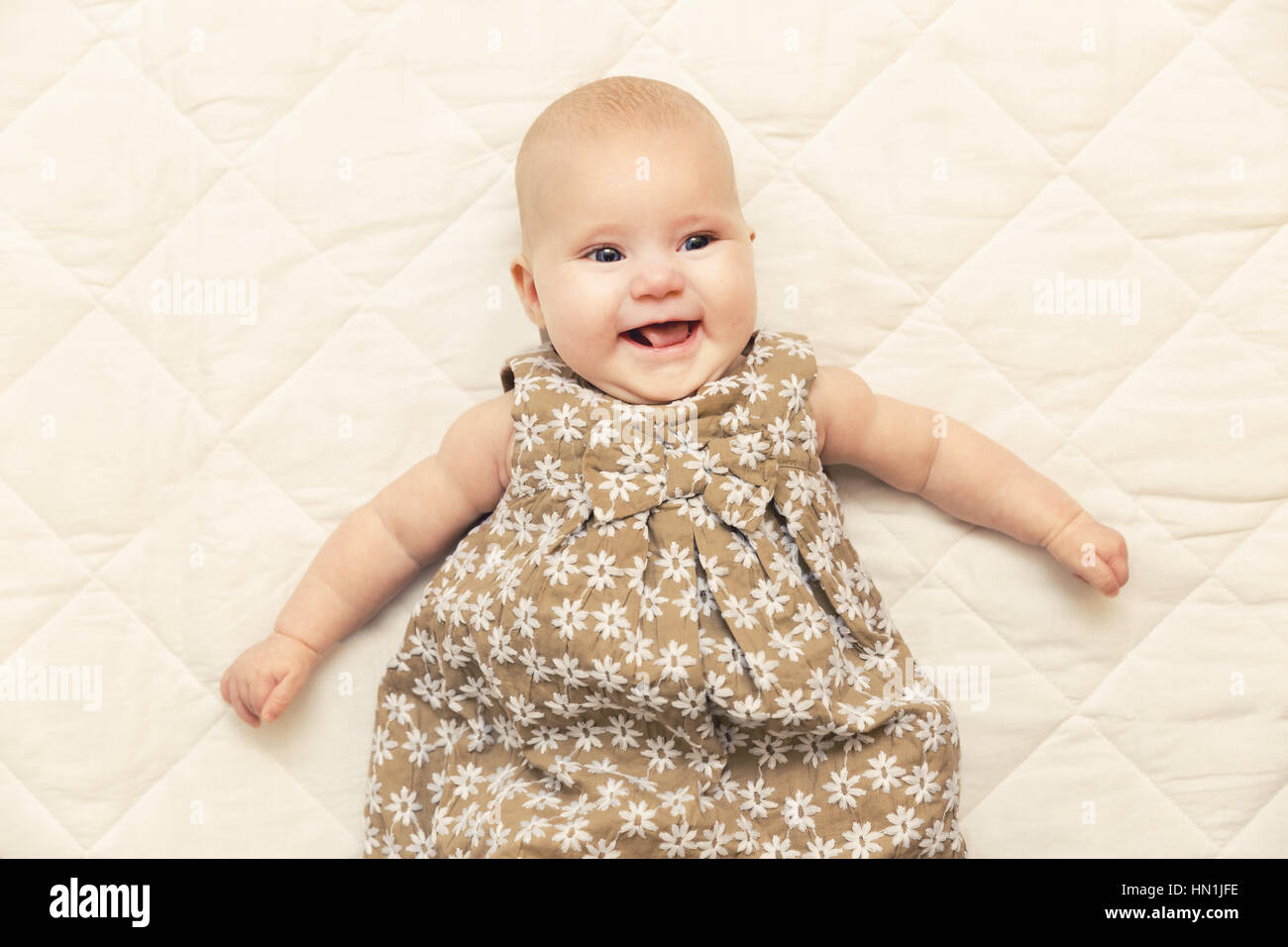 Sorridenti Baby girl su una coperta a letto Foto Stock
