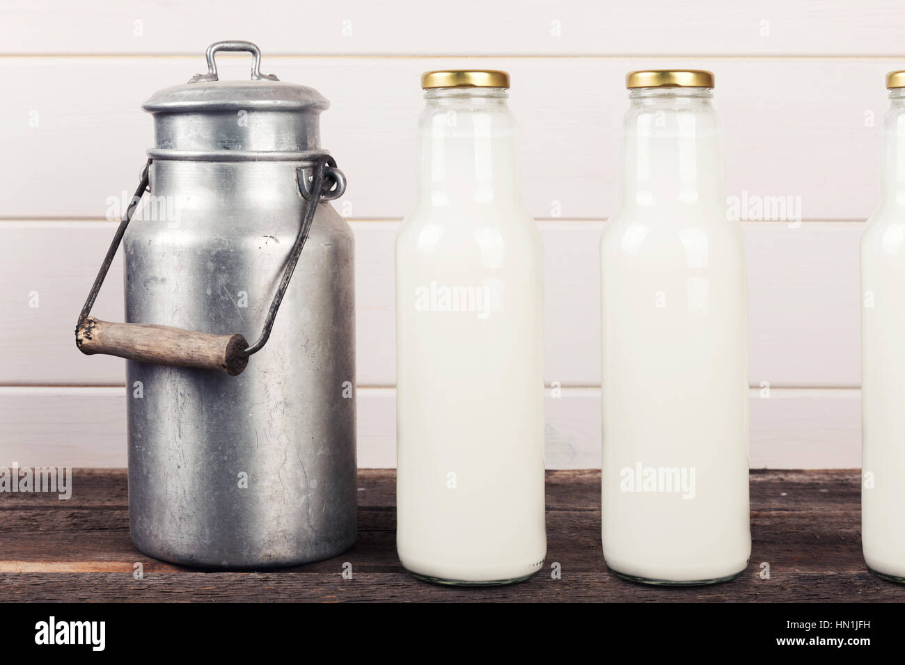 Vecchio latte può e bottiglie sul tavolo di legno Foto Stock