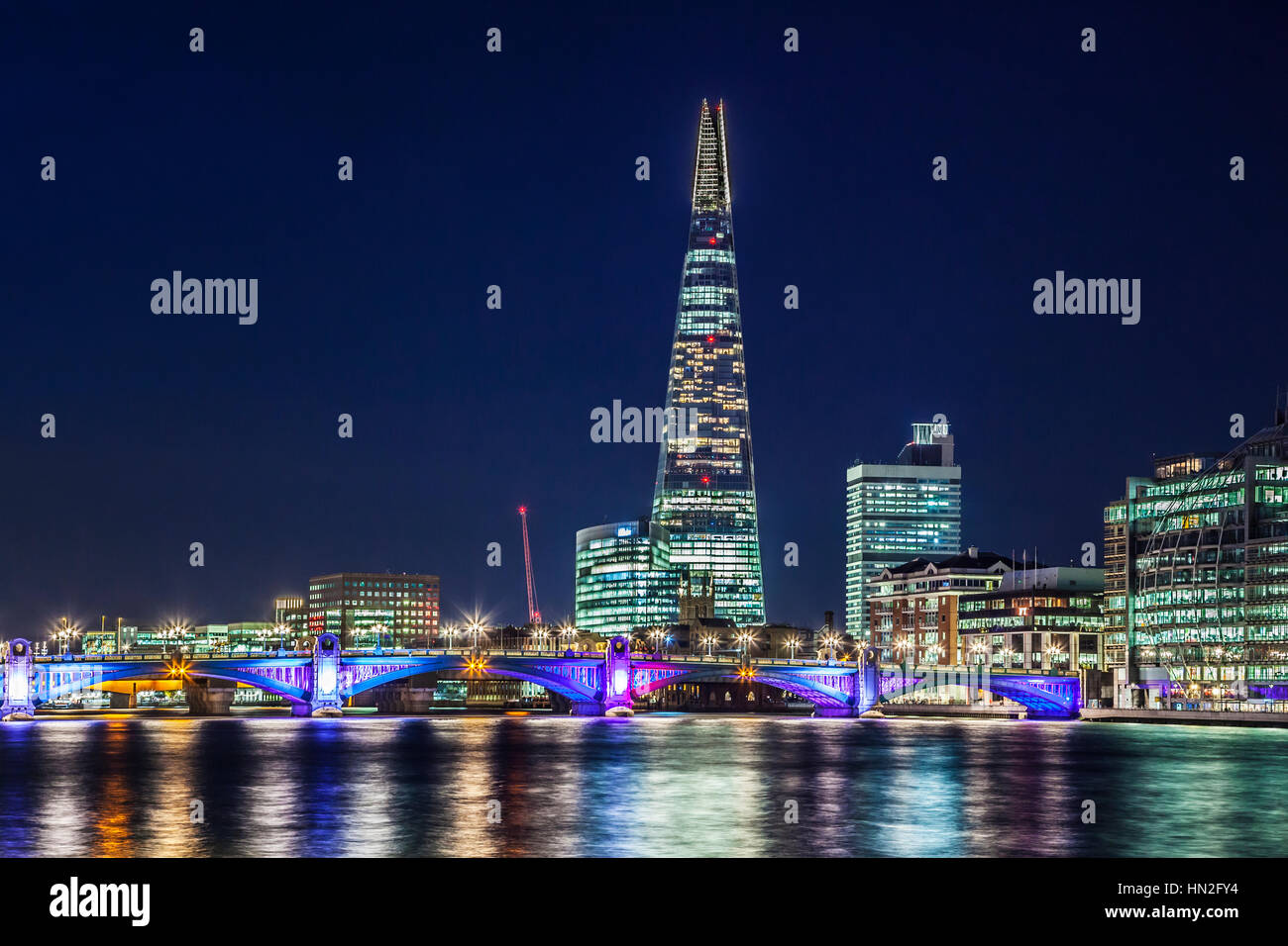 Vista del fiume Tamigi verso Southwark Bridge e il coccio di notte. Foto Stock