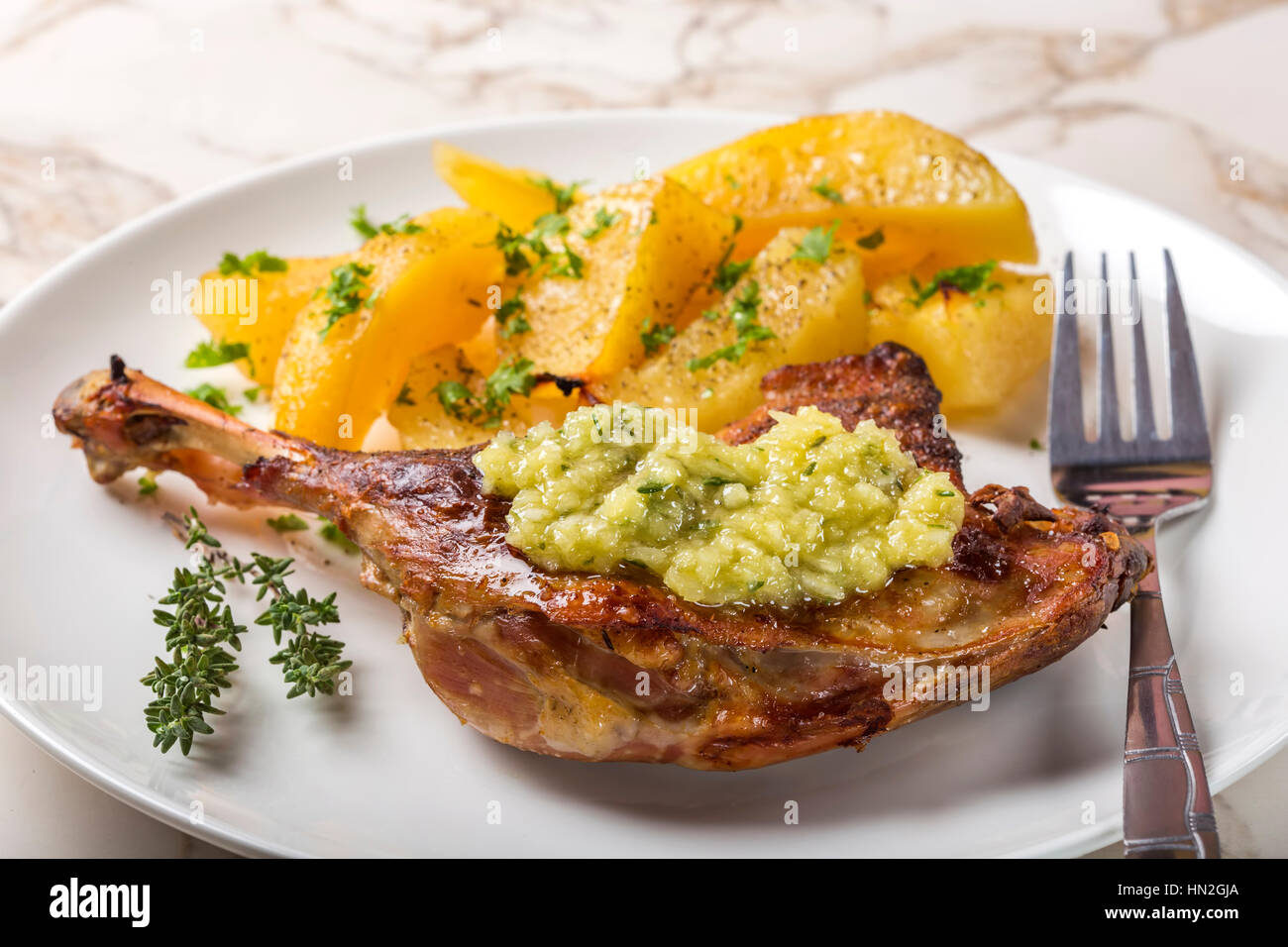 Anatra arrosto con patate dorate e salsa di aglio con le erbe su piastra Foto Stock