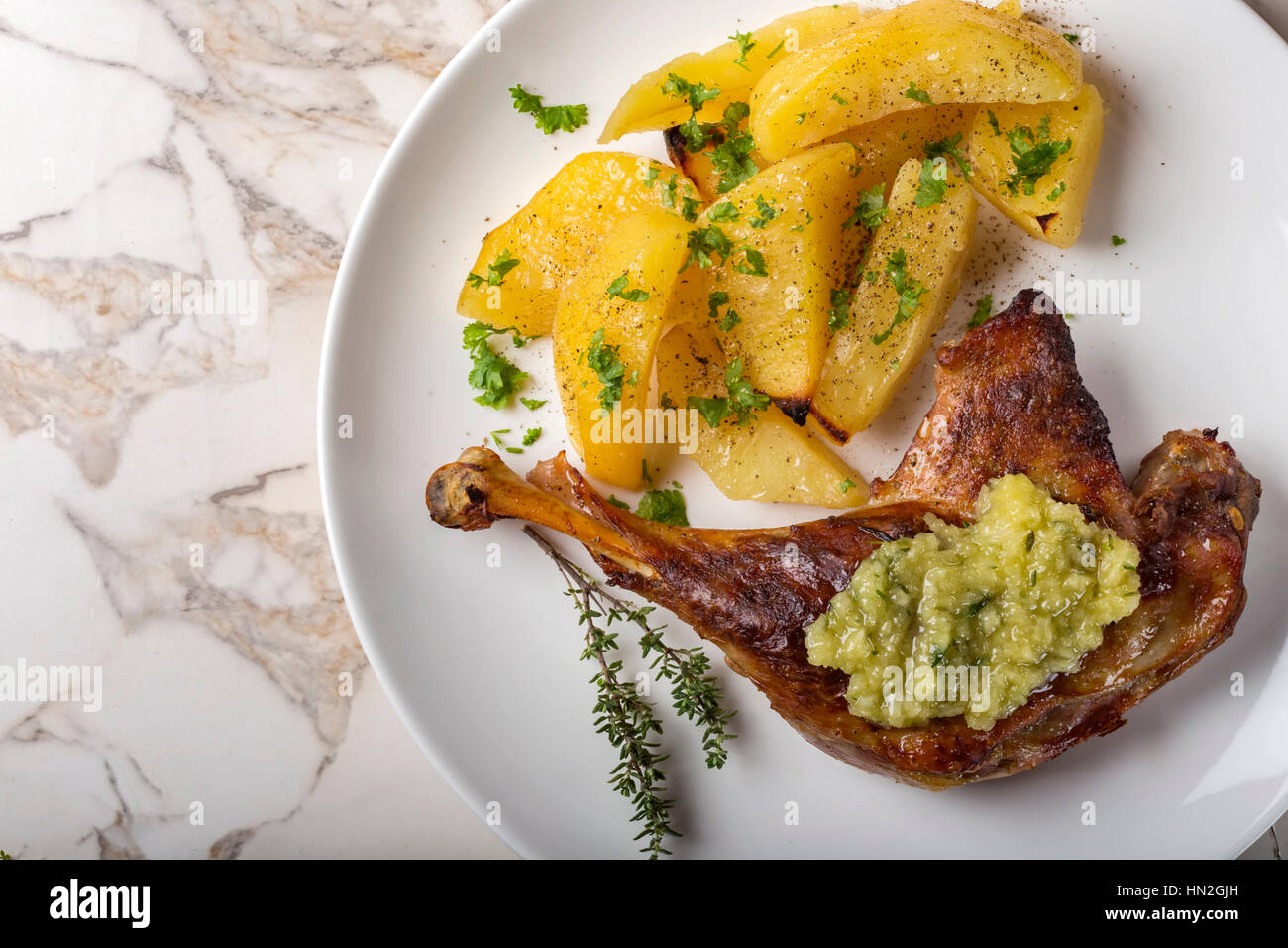 Anatra arrosto con patate dorate e salsa di aglio con le erbe su piastra Foto Stock