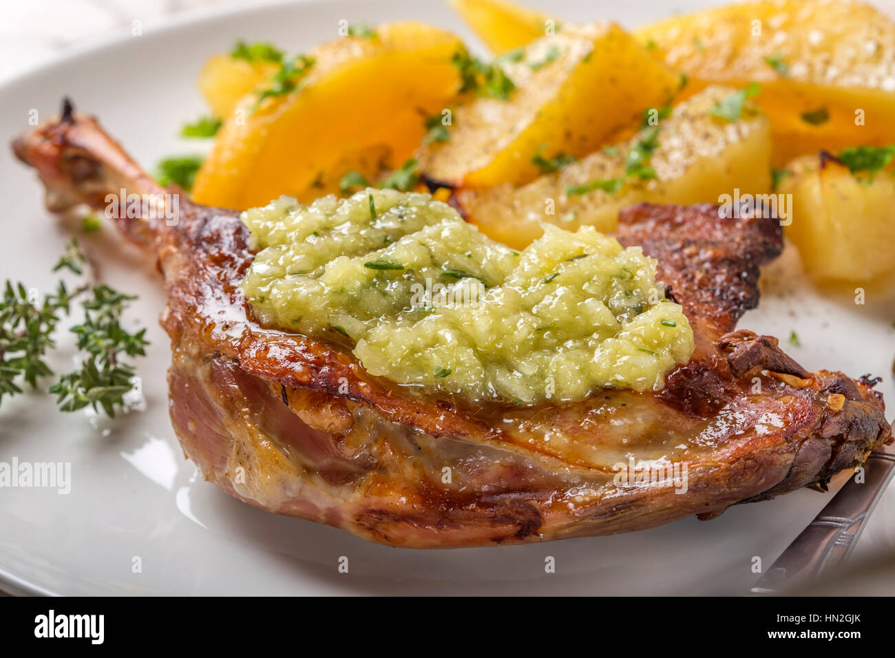 Close up di anatra arrosto con patate dorate e salsa di aglio con le erbe su piastra Foto Stock