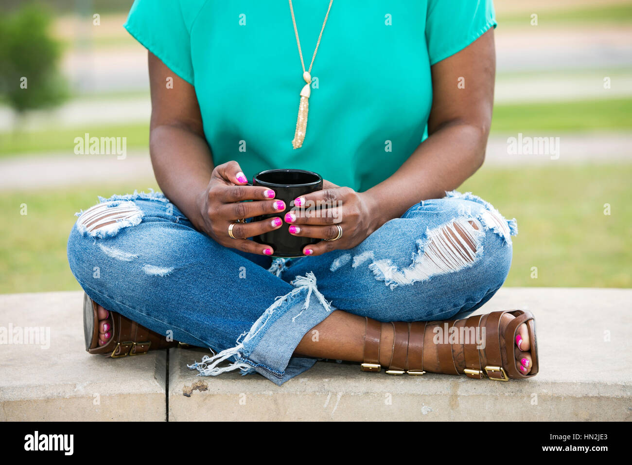 Bella americano africano donna tenendo una tazza di tè, sfondo estate parco verde nel centro di Austin, Texas, Stati Uniti d'America Foto Stock