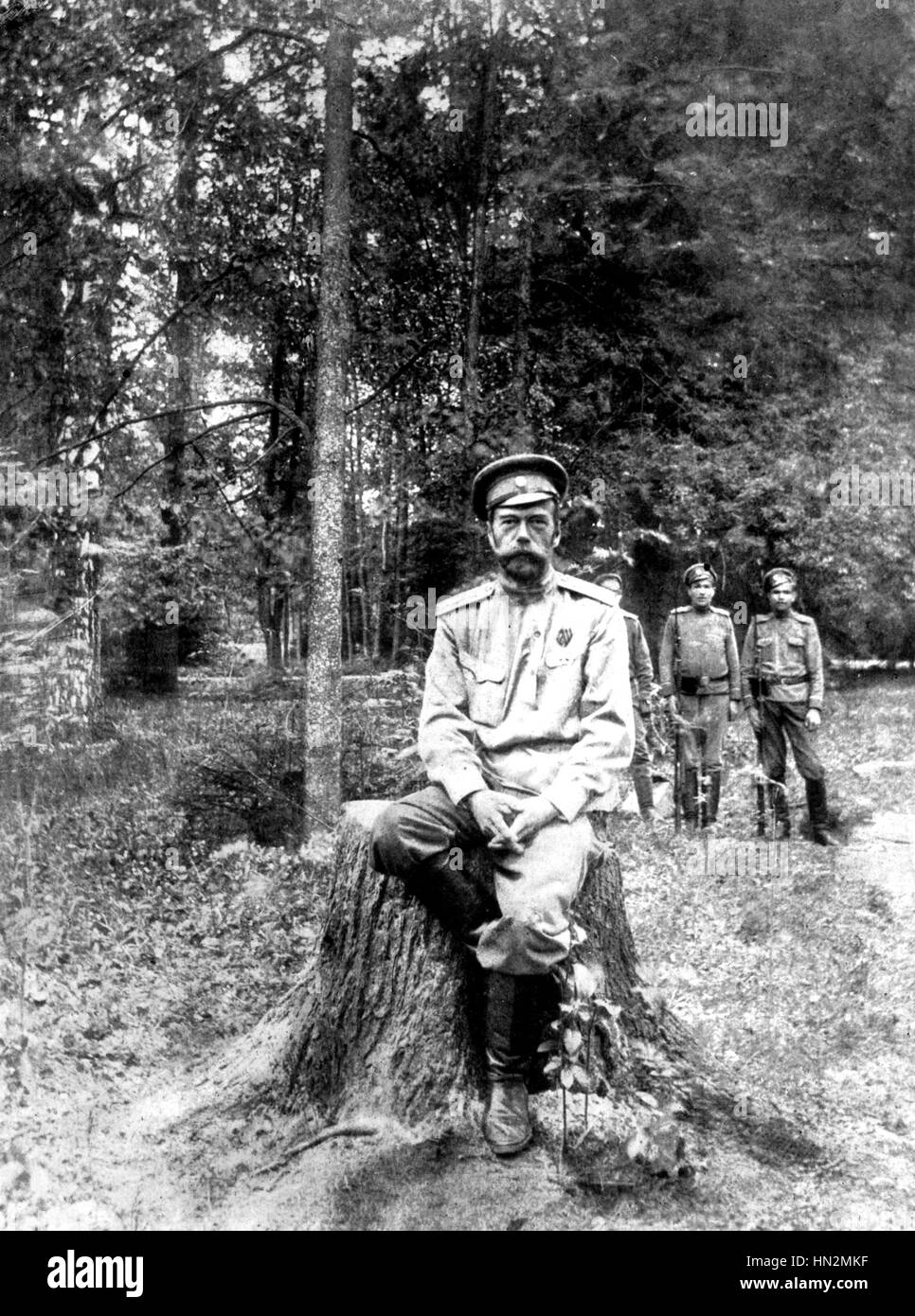 L'ex-imperatore di Russia, Nicholas II, seduto su un tronco di albero custodito da due soldati. Carskoe Selo (Pushkin), nei pressi di San Pietroburgo. 1917 la Russia Foto Stock