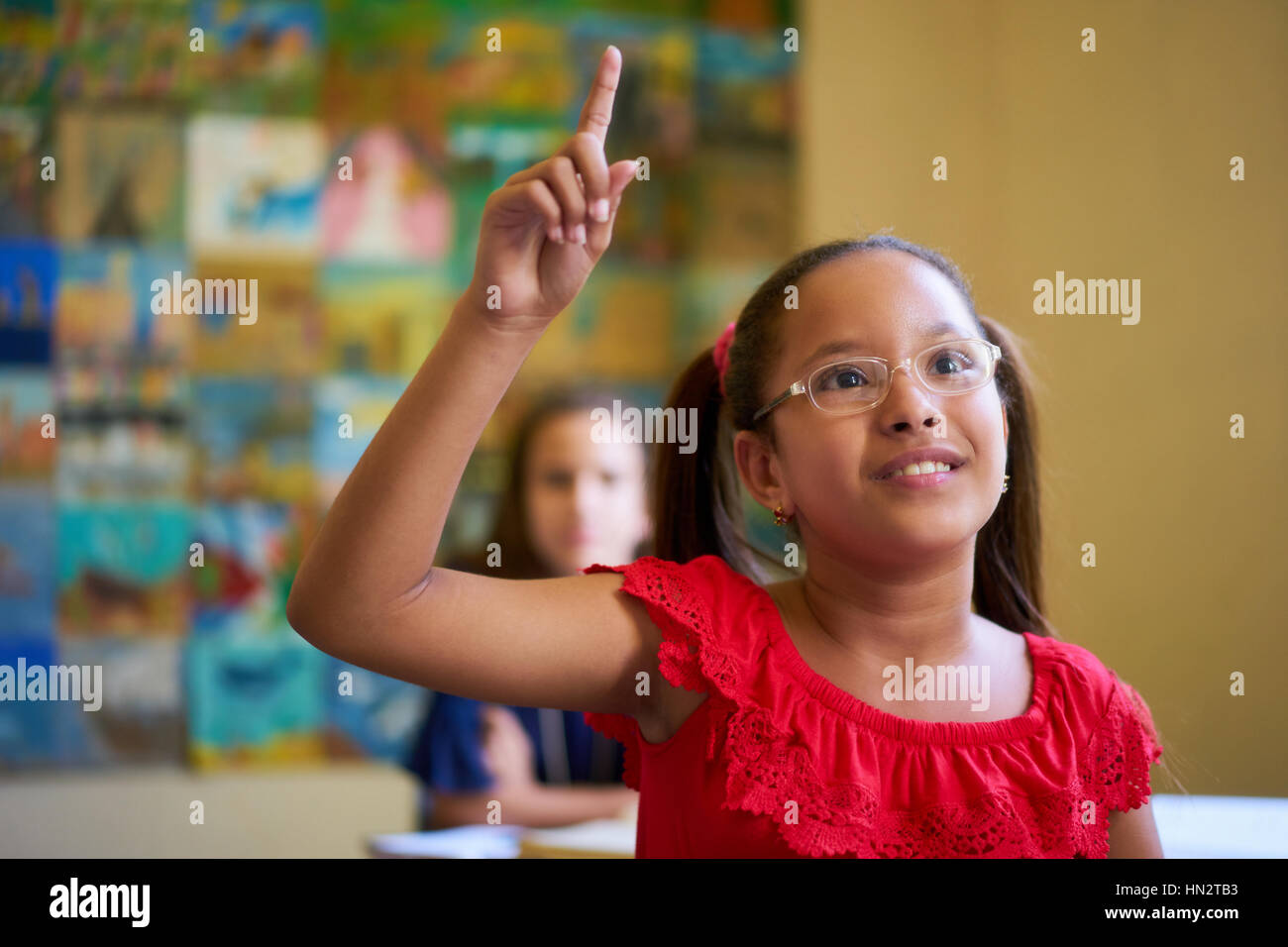 I giovani e l'istruzione. Gruppo di studenti ispanici in classe a scuola durante la lezione. Ragazza intelligente con occhiali alzando la mano Foto Stock