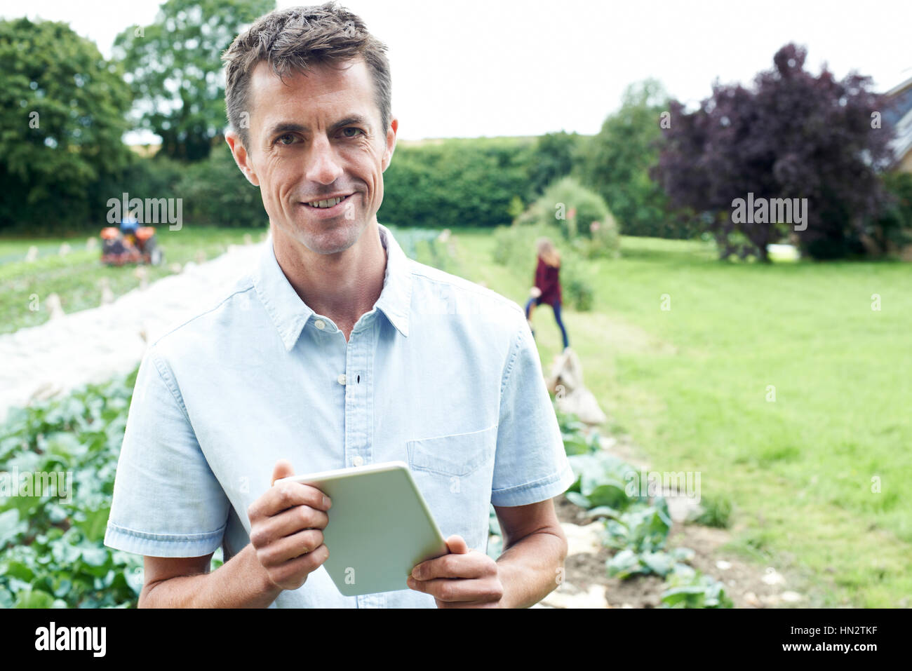 Maschio lavoratore agricolo utilizzando tavoletta digitale nel campo Foto Stock