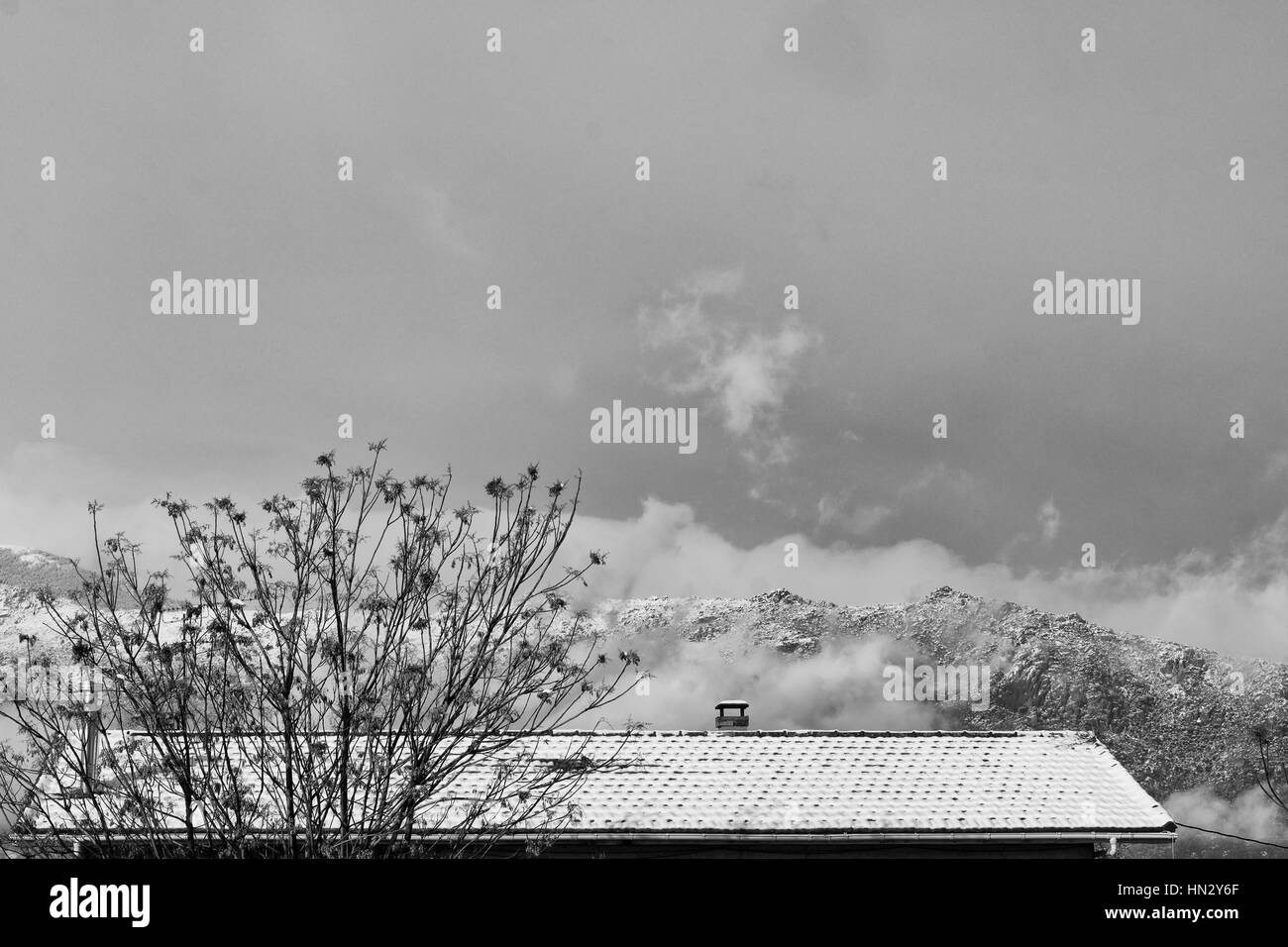 Tetto innevate sullo sfondo le montagne in inverno tempo. Oggetto catturati nel corso di tempesta di neve Foto Stock