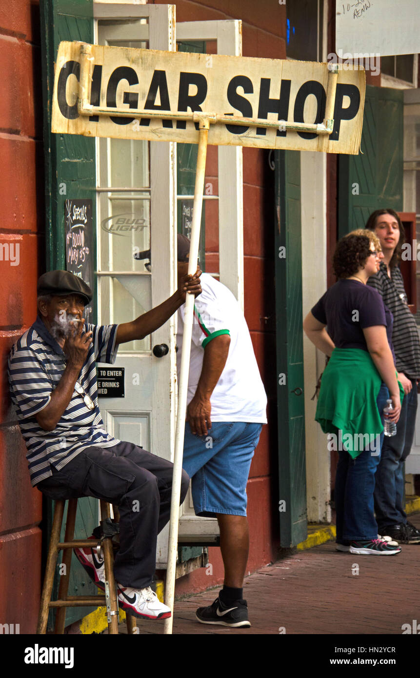 New Orleans, Stati Uniti d'America - 13 Luglio 2015: afro-americano di uomo fuma sigarette e detiene un annuncio firmare e allettanti i clienti davanti a un negozio di sigari in nuovi o Foto Stock