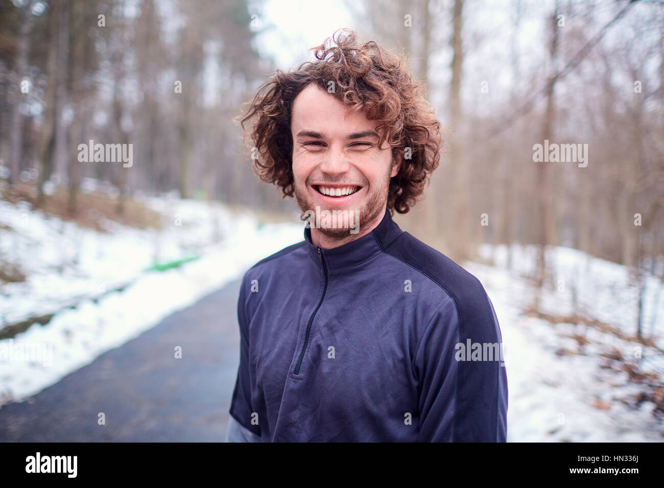 Giovane uomo sorridente ricci felice all'aperto in primavera, autunno closeup Foto Stock