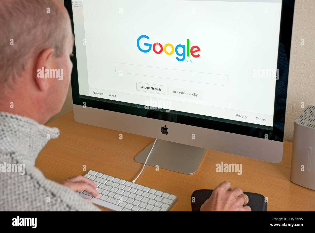 Uomo che guarda Google UK homepage sullo schermo del computer. Foto Stock
