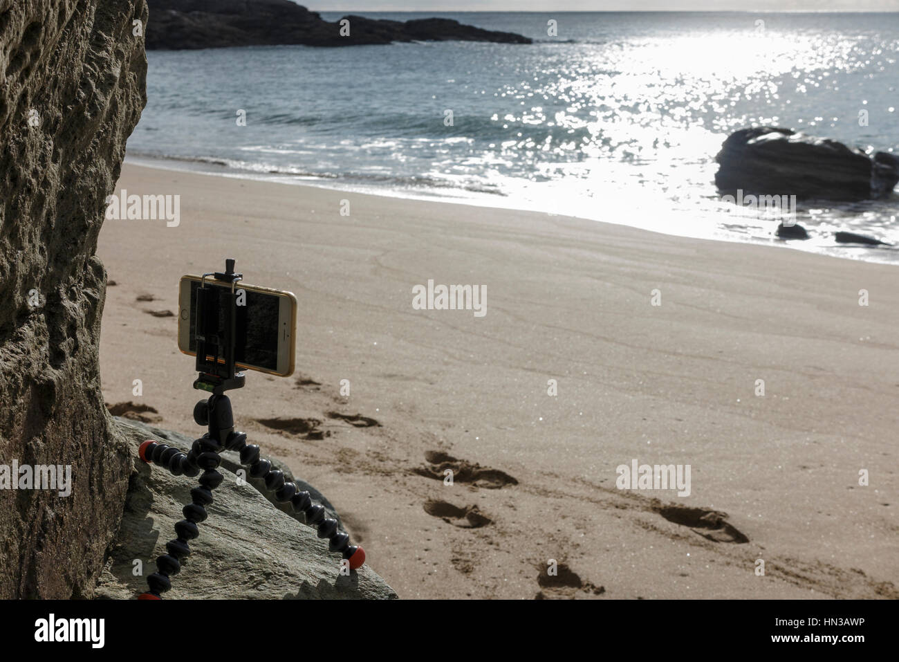 Utilizzando un piccolo 'GorillaPod' treppiede con un iphone per fotografare beach in Devon Foto Stock