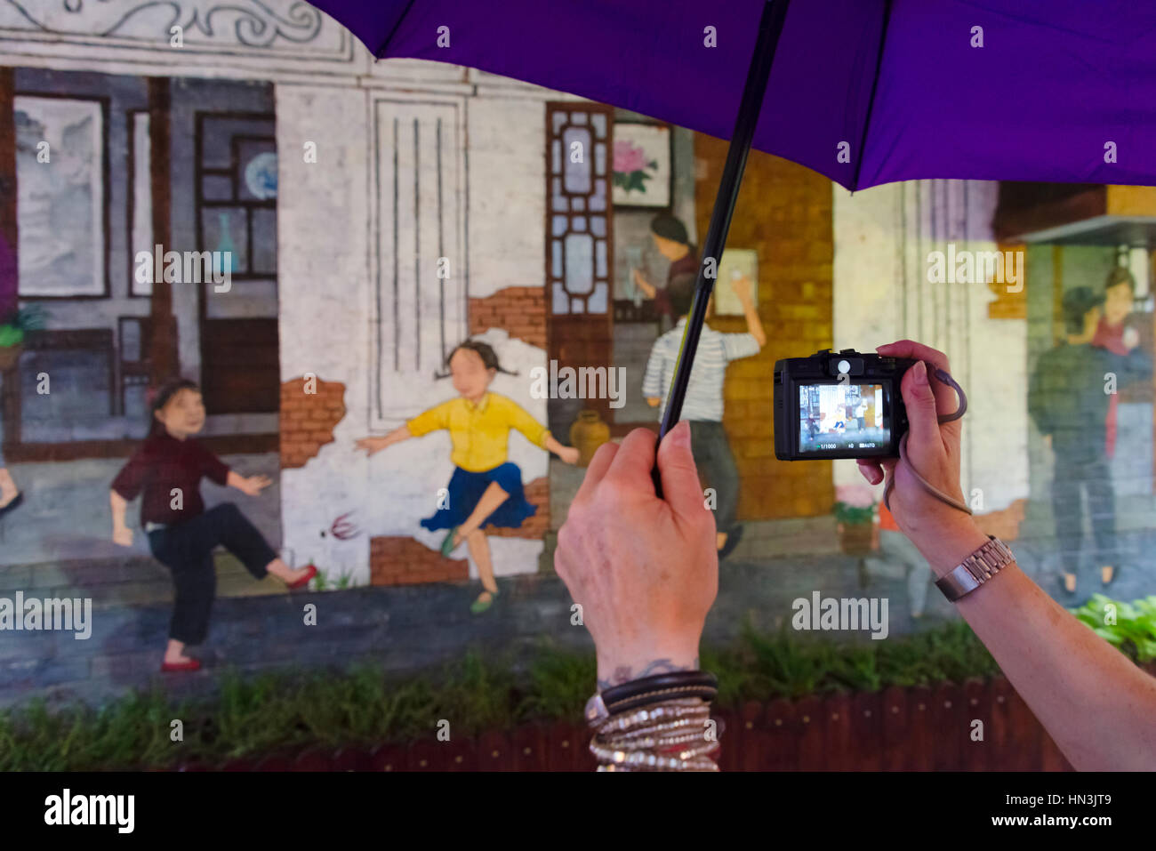 Turistico con ombrello fotografare murale di Tianzifang, un arti e mestieri enclave della concessione francese area, Shanghai, Cina Foto Stock