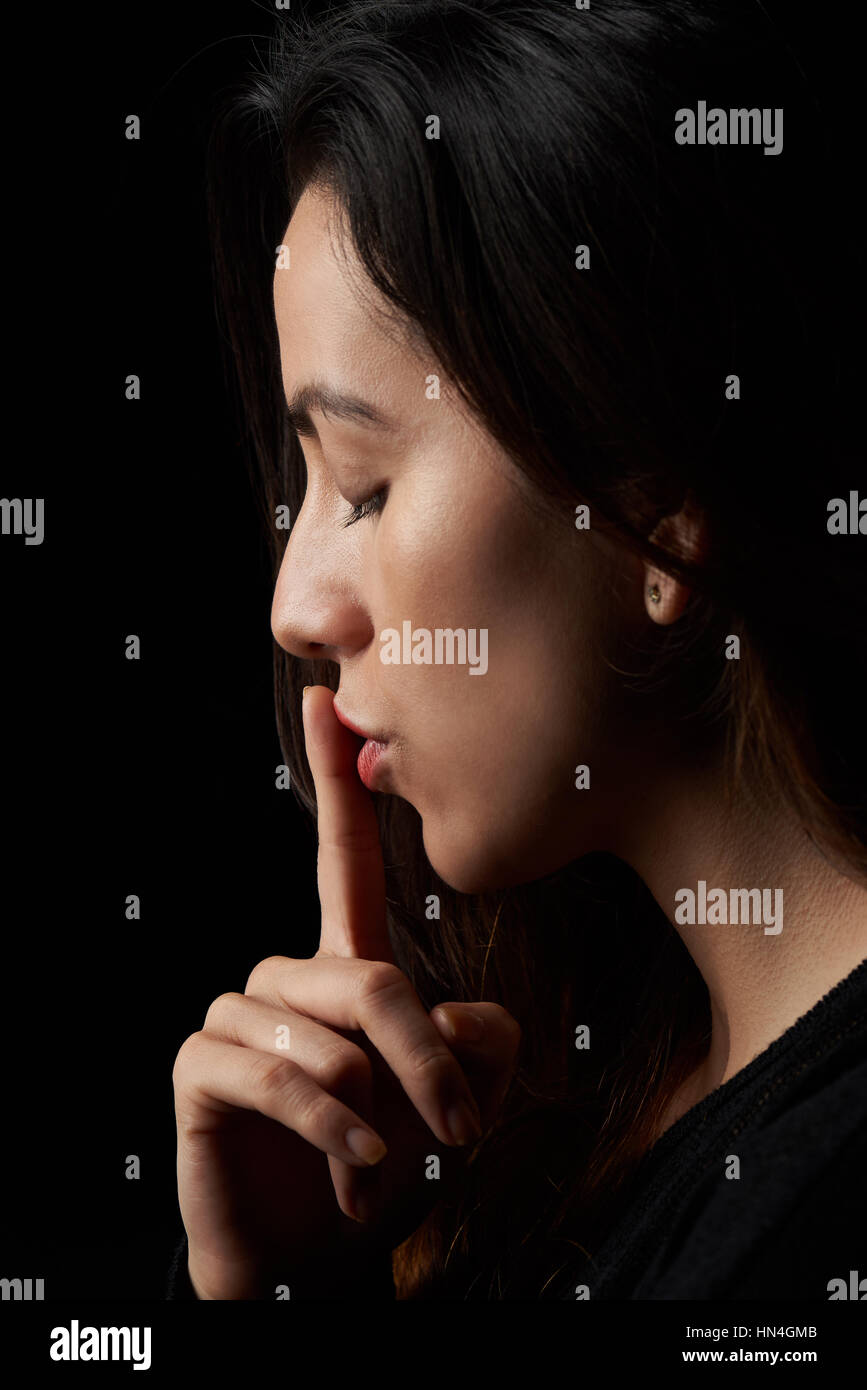 Profilo di donna con il dito accanto a labbra Foto Stock