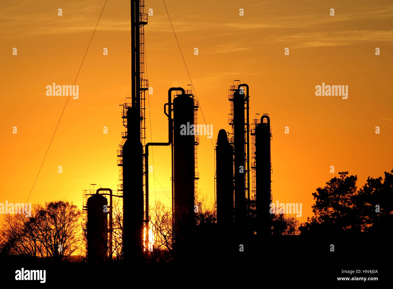 Silhouette di raffineria di petrolio contro il sole Foto Stock
