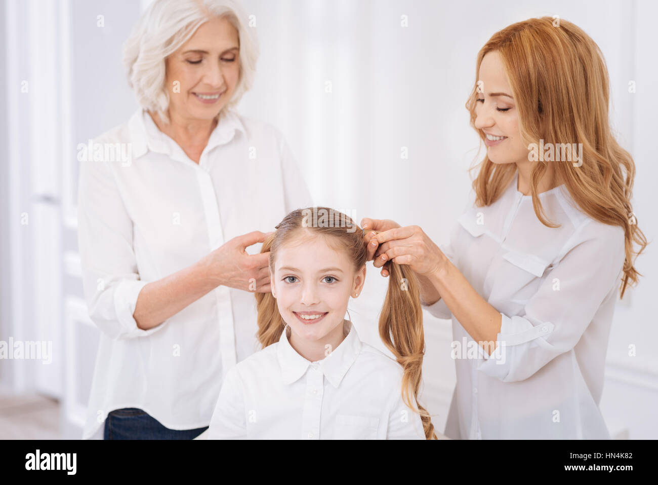 Positivi i membri di famiglia rendendo ponytails per bambina Foto Stock