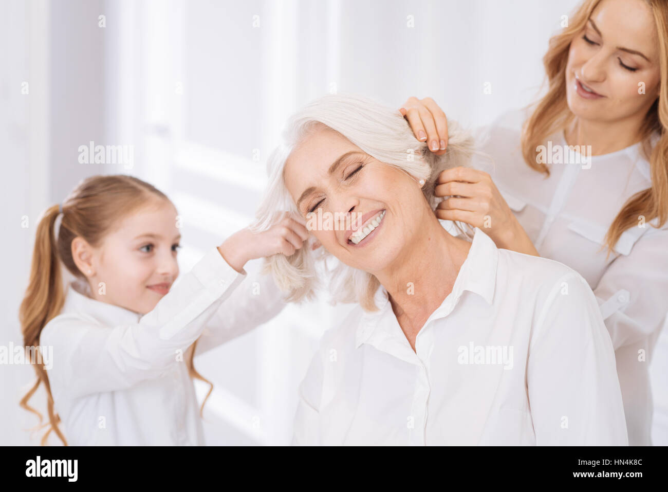 Positivo donna invecchiato in appoggio a casa con i membri della sua famiglia Foto Stock