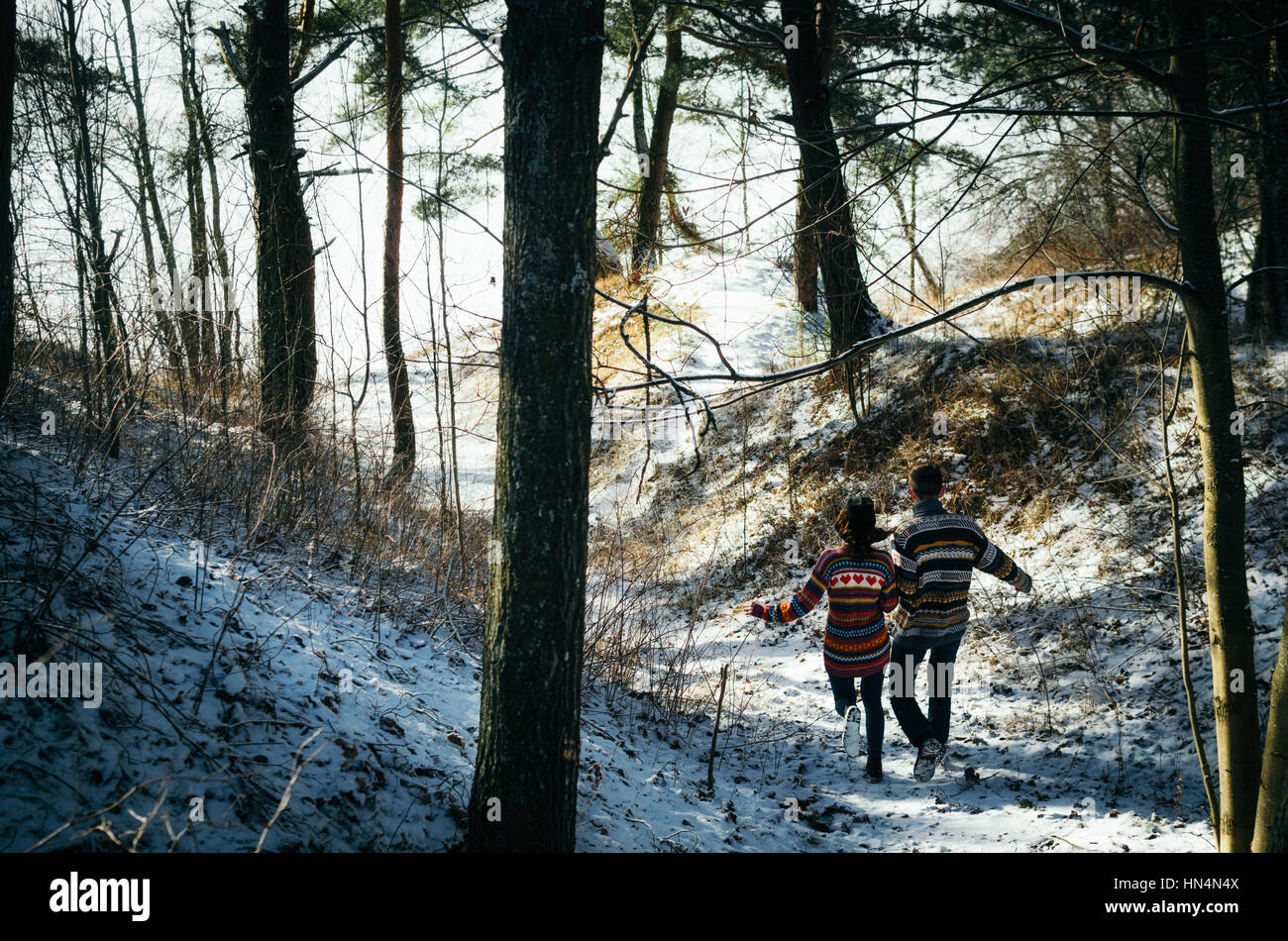 Giovane holding hands fuggire alla foresta in inverno Foto Stock