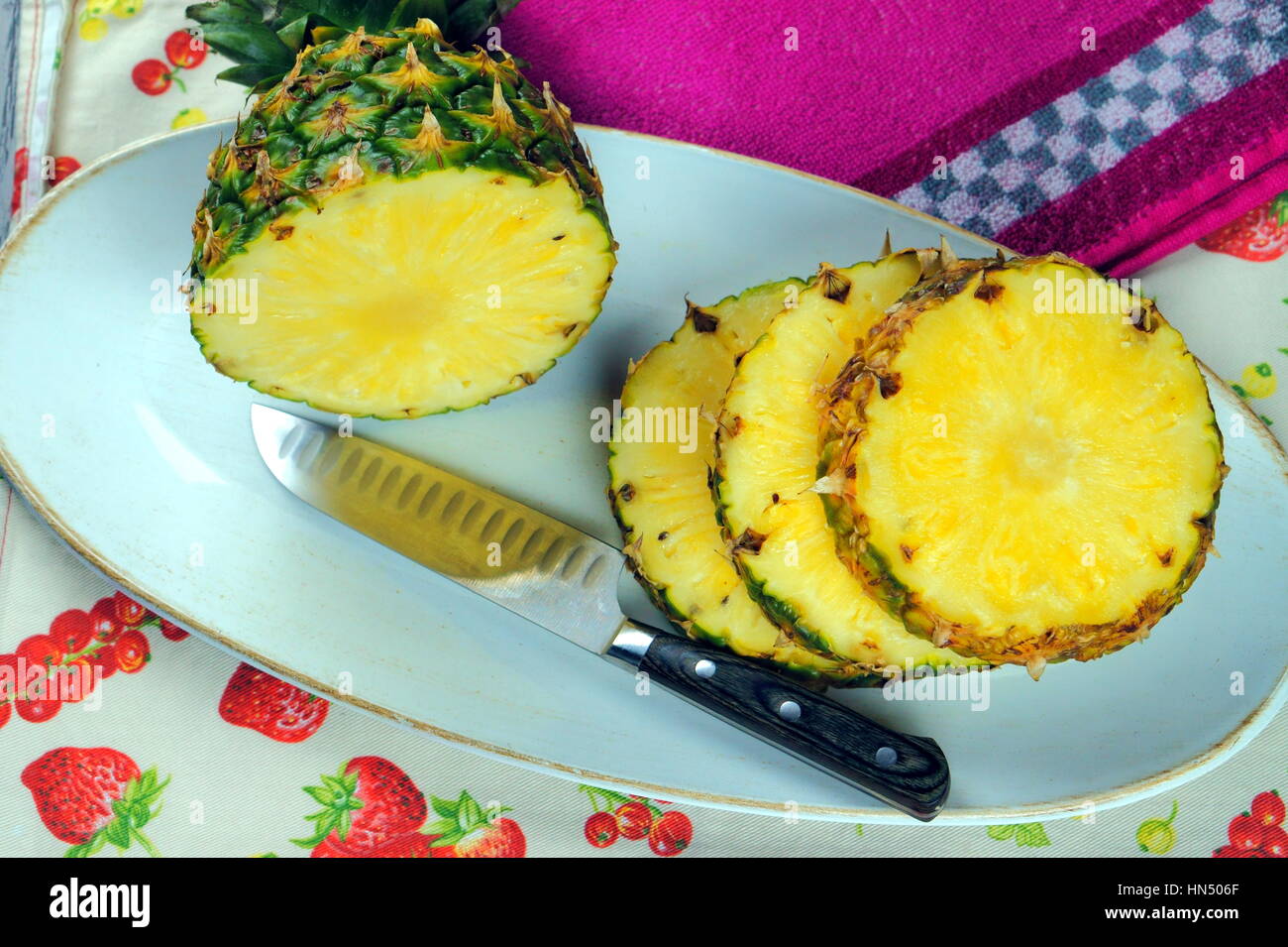 Tagliare ananas e posate (lama) servita in un piatto bianco sulla colorata biancheria per la cucina - cibo organico serie Foto Stock