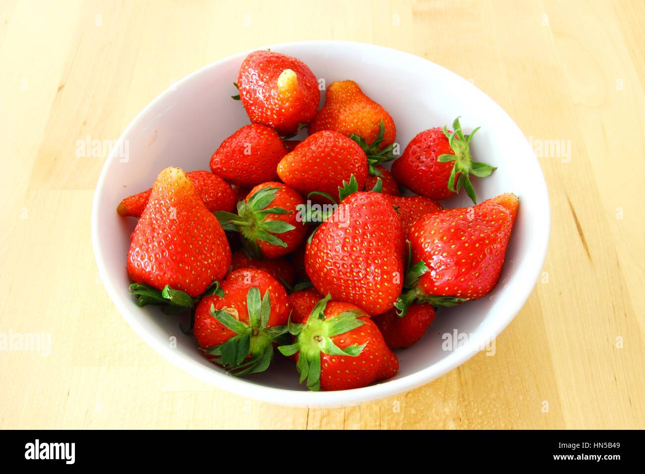 Le fragole in bianco ciotola sul tavolo di legno Foto Stock