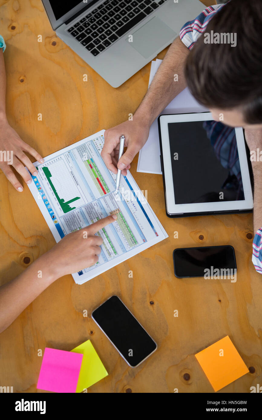 I dirigenti aziendali a discutere di tabelle e grafici sulla scrivania in ufficio Foto Stock