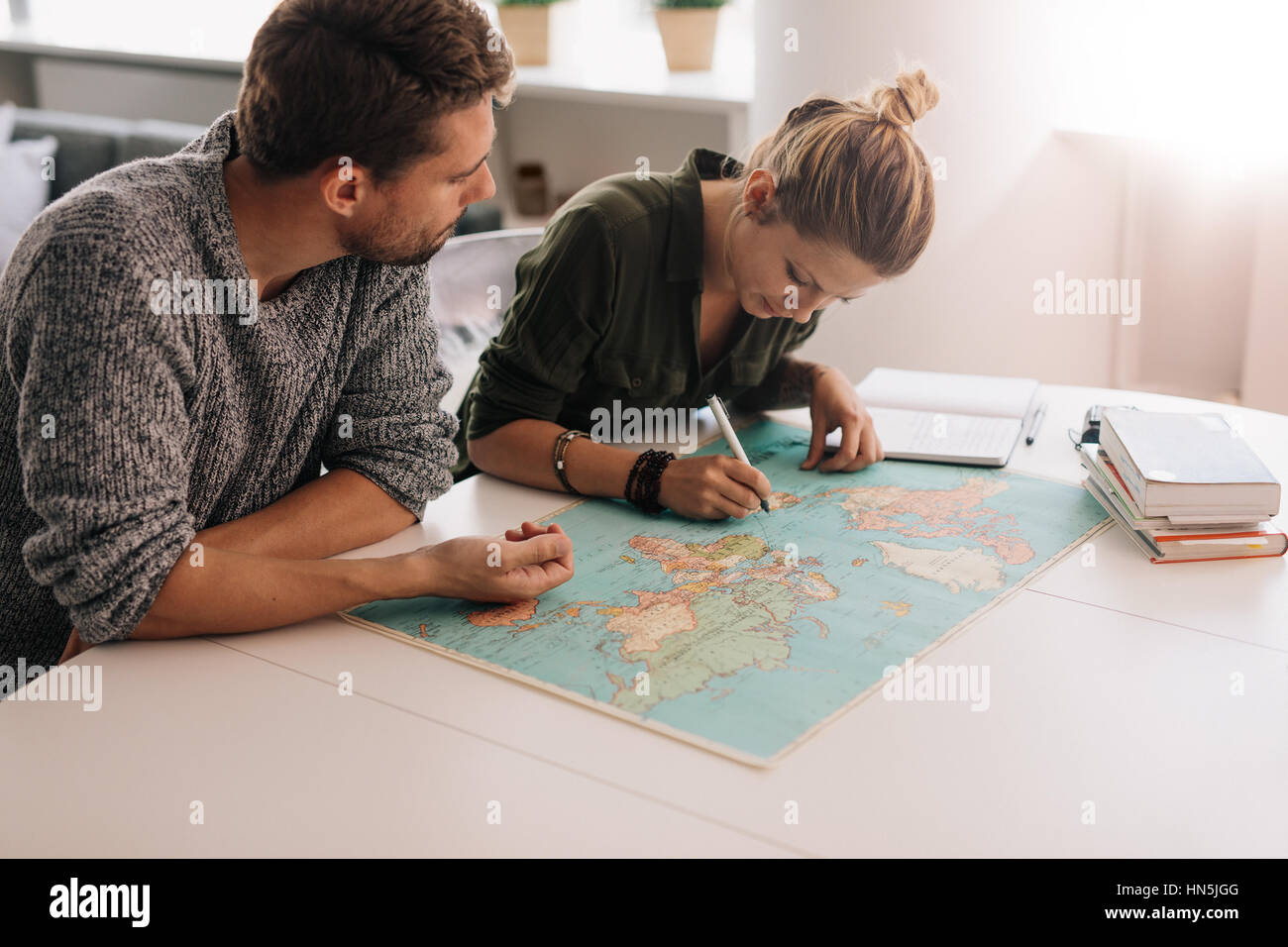 L uomo e la donna a studiare la mappa del mondo e prendere appunti. Marcatura di donna sulla mappa del mondo utilizzando una penna. Foto Stock
