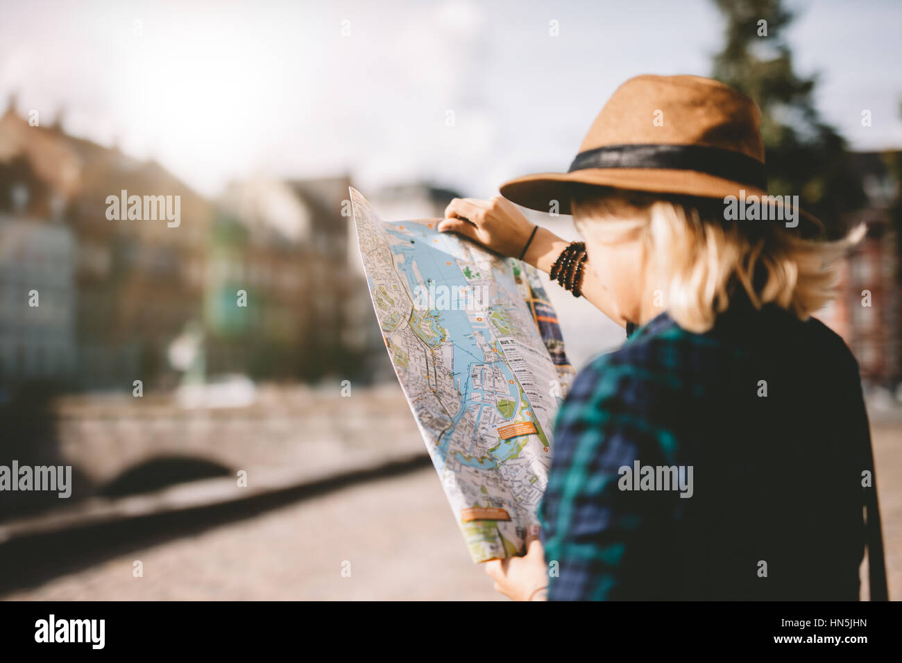 Vista laterale della giovane donna indossa hat guardando una mappa della città. Per turisti in cerca di rotta di navigazione sulla mappa. Foto Stock