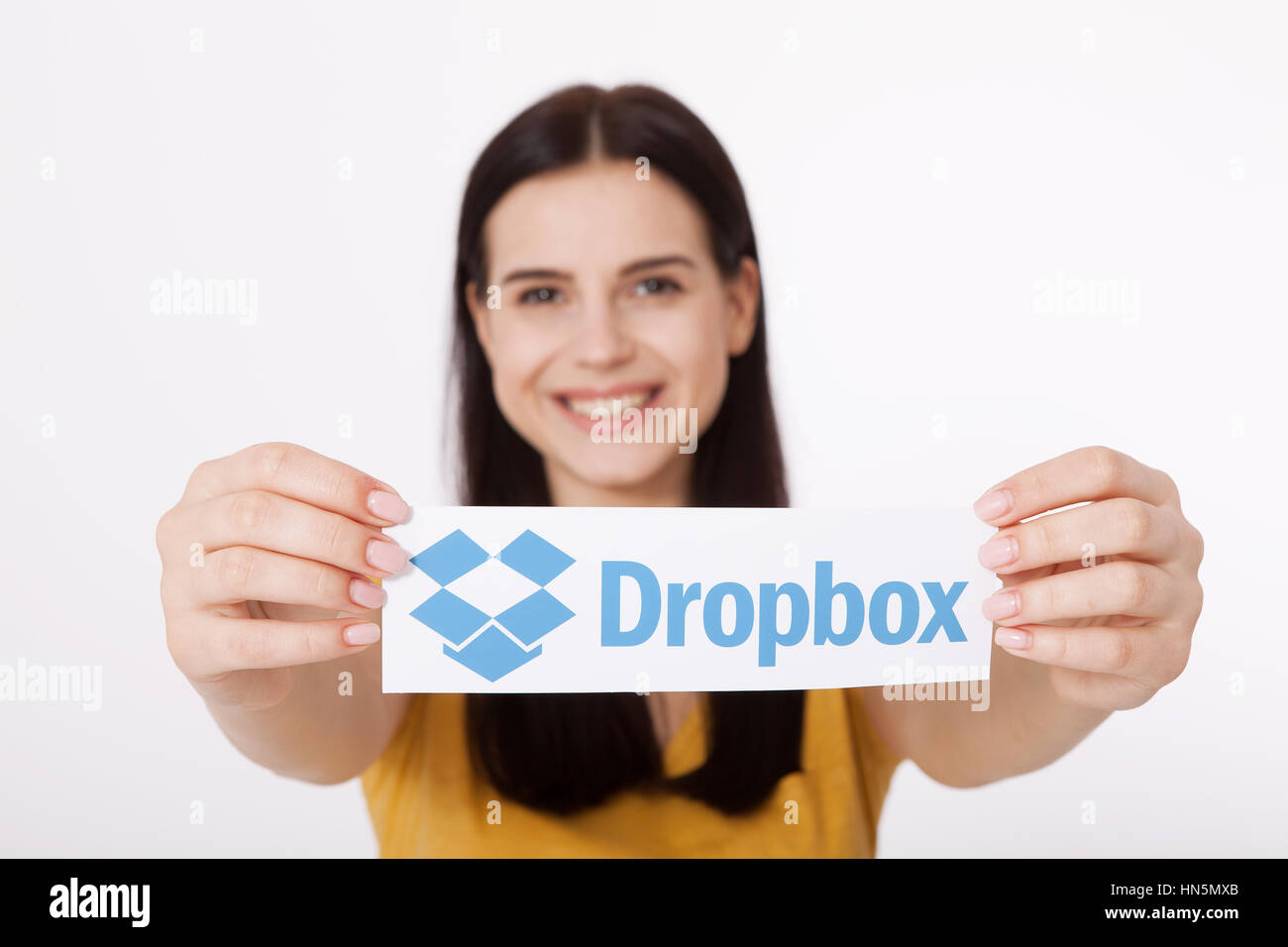 KIEV, UCRAINA - 22 agosto 2016: Donna mani Dropbox logotipo segno stampato su carta su sfondo bianco. Dropbox cloud storage, consentendo agli utenti di archiviare i dati sui server in cloud. Foto Stock