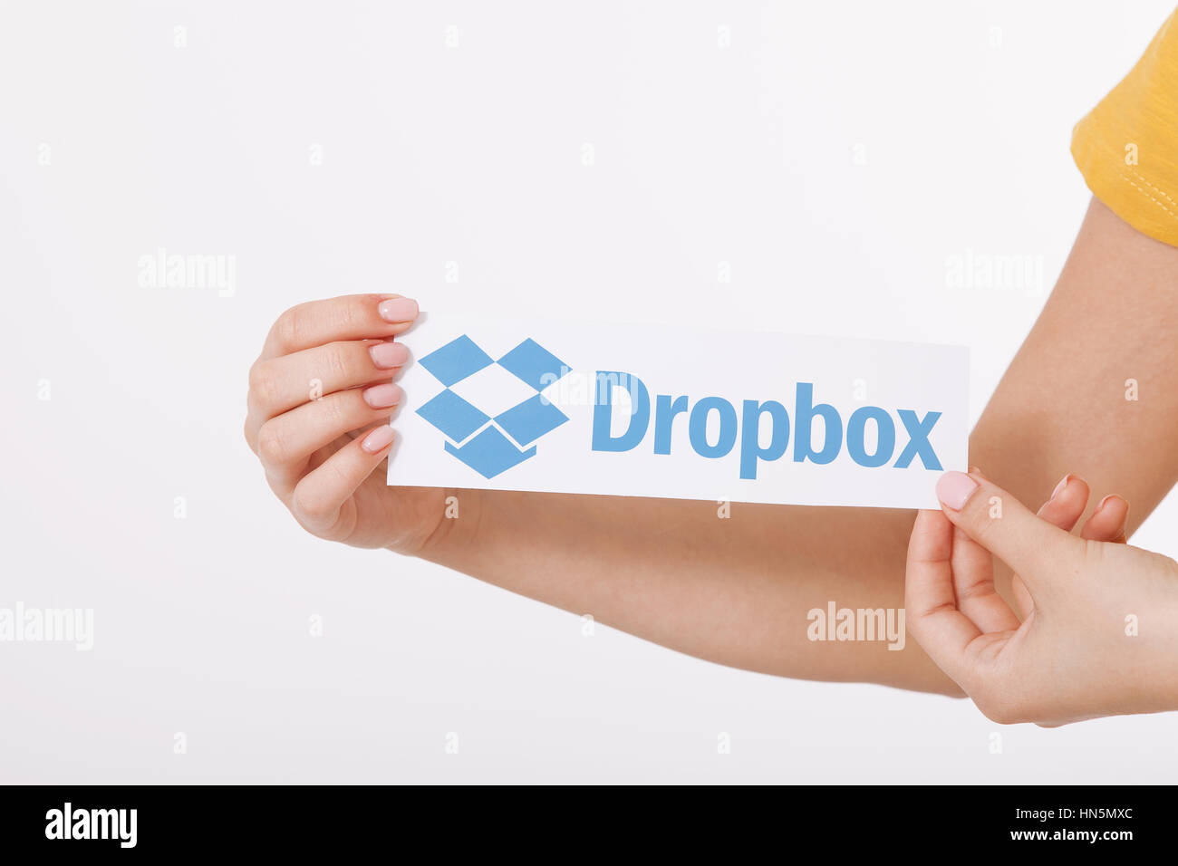 KIEV, UCRAINA - 22 agosto 2016: Donna mani Dropbox logotipo segno stampato su carta su sfondo bianco. Dropbox cloud storage, consentendo agli utenti di archiviare i dati sui server in cloud. Foto Stock