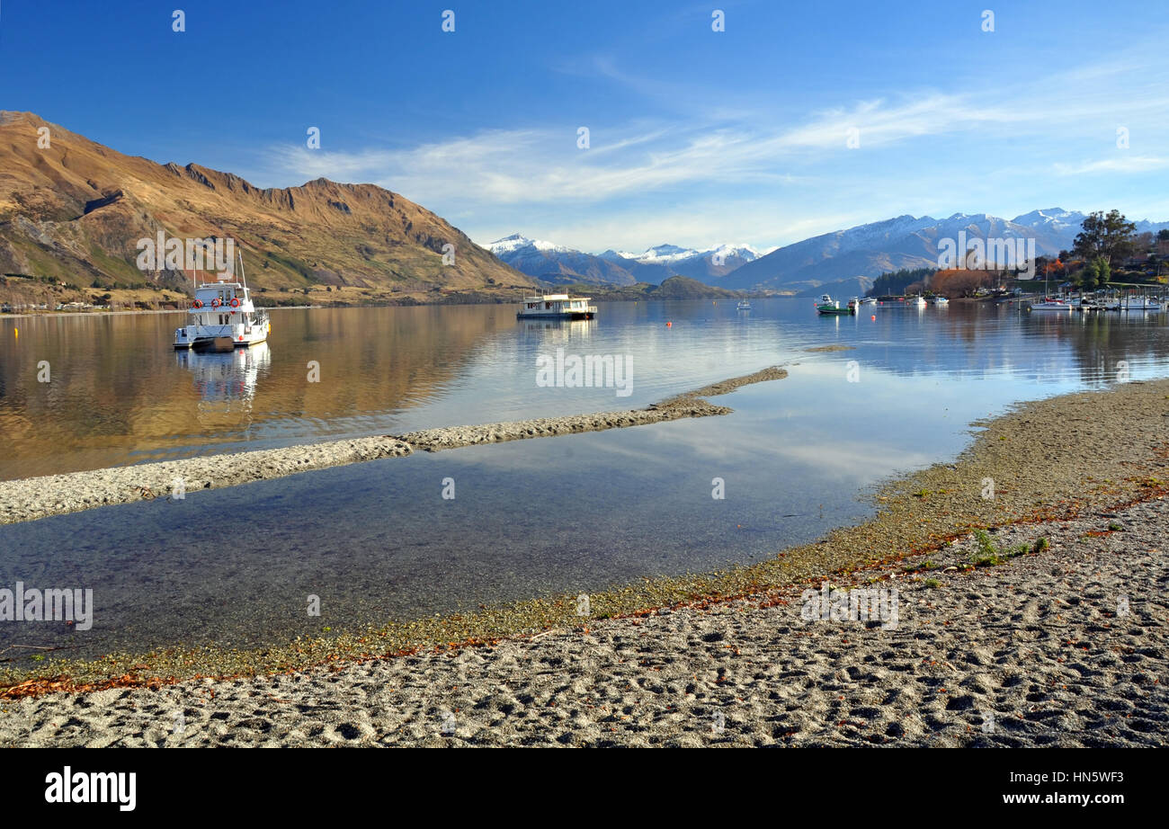 Il lago Wanaka e barche con il Sud delle Alpi in background. Central Otago, Nuova Zelanda. In primo piano nota come basso il livello del lago è dopo uno Foto Stock