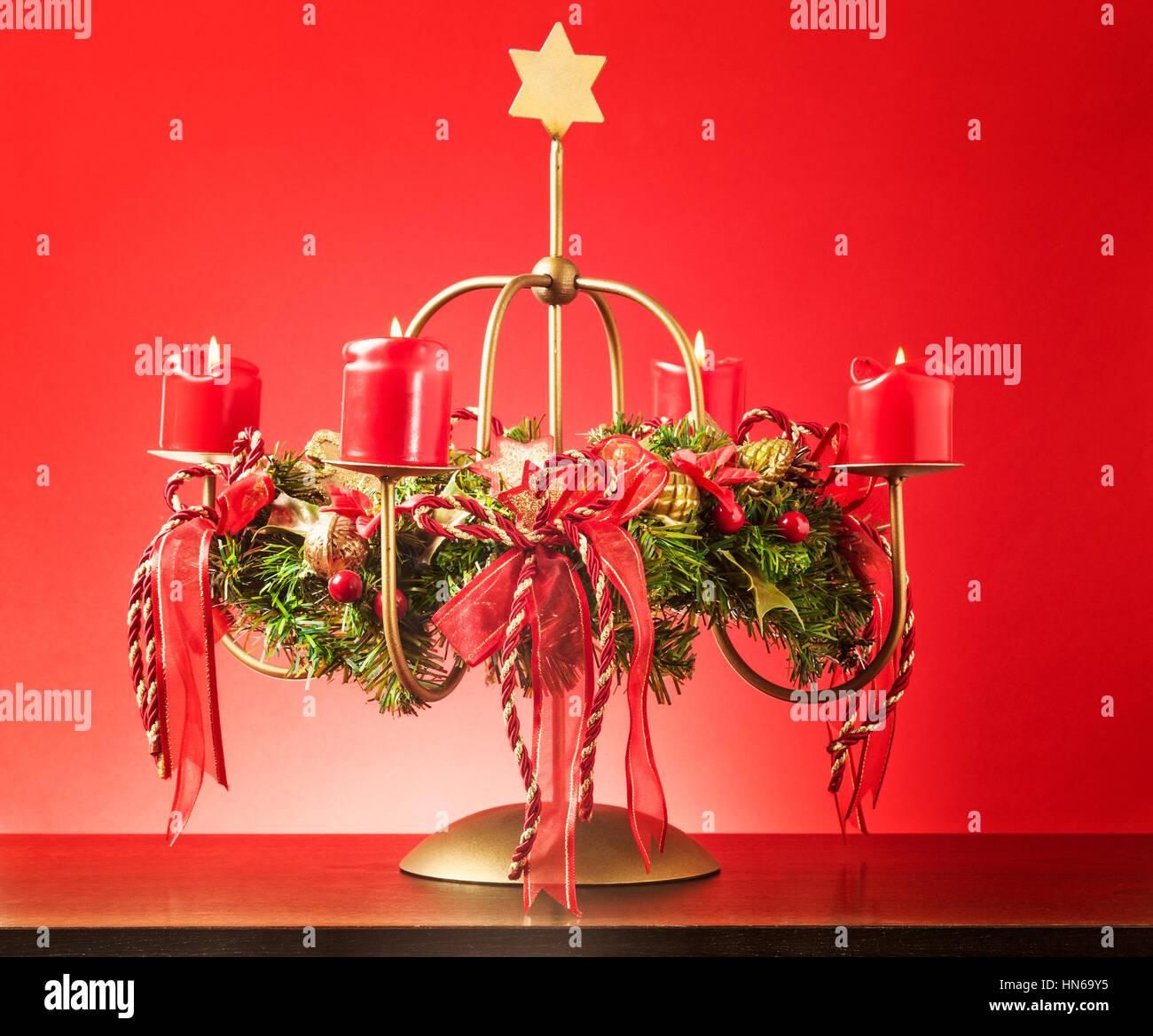 Vintage corona di Avvento con quattro candele accese e stelle d'oro su sfondo rosso, luci e decorazioni per il tempo di Natale Foto Stock