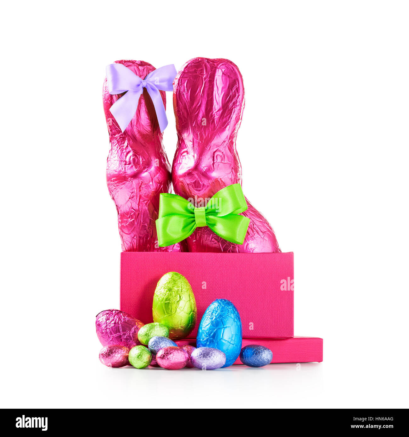Confezione regalo con le uova di Pasqua di cioccolata, coppia di conigli con archetto, avvolto nel foglio rosa e caramelle colorate isolati su sfondo bianco tracciato di ritaglio Foto Stock
