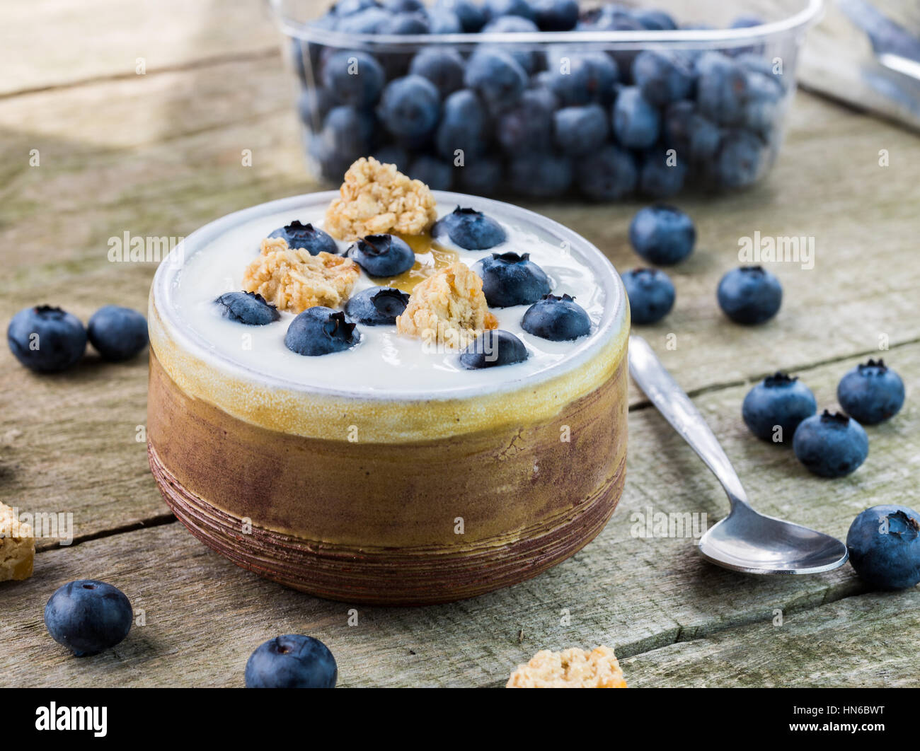 Yogurt bianco con mirtilli sulla parte superiore nella ciotola di legno naturale tabella. Foto Stock