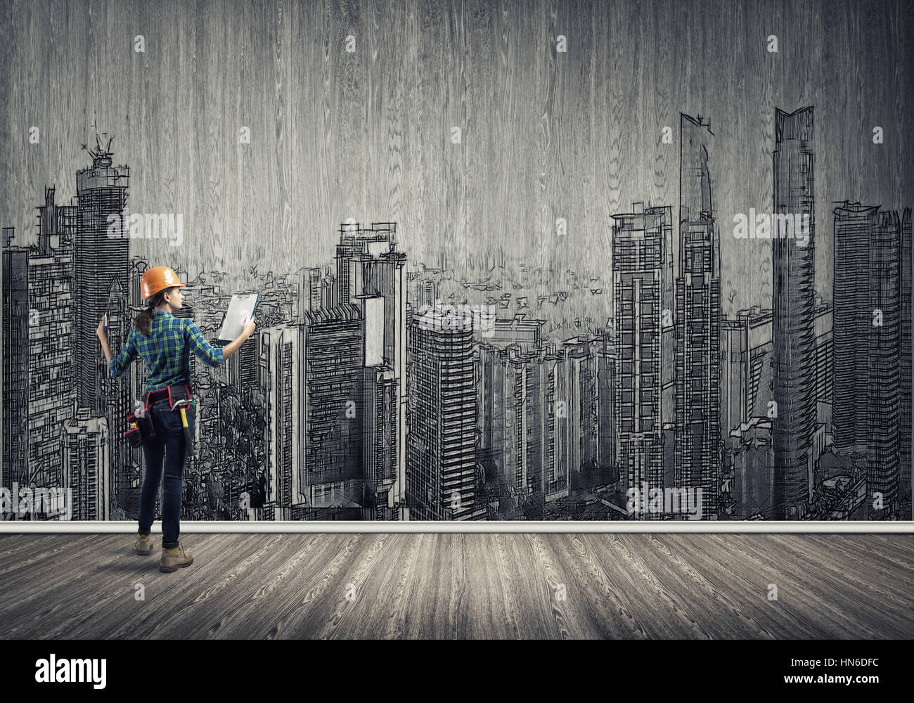 Vista posteriore di ingegnere di donna con la cartella e schizzi di progetto di costruzione sulla parete Foto Stock