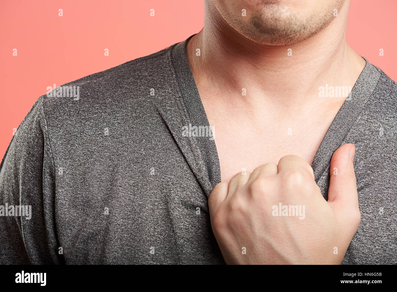 Close up man mano tirando maglietta grigio Foto Stock
