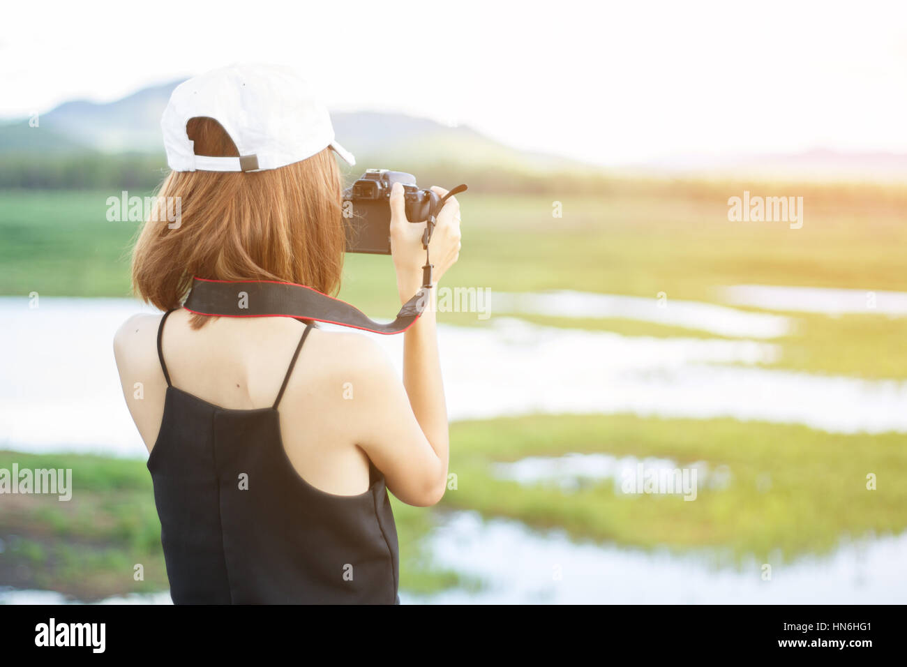 Asia ragazza scatta foto in natura hanno la montagna e l acqua in background. Messa a fuoco selettiva e morbida luce del sole di svasatura. Foto Stock