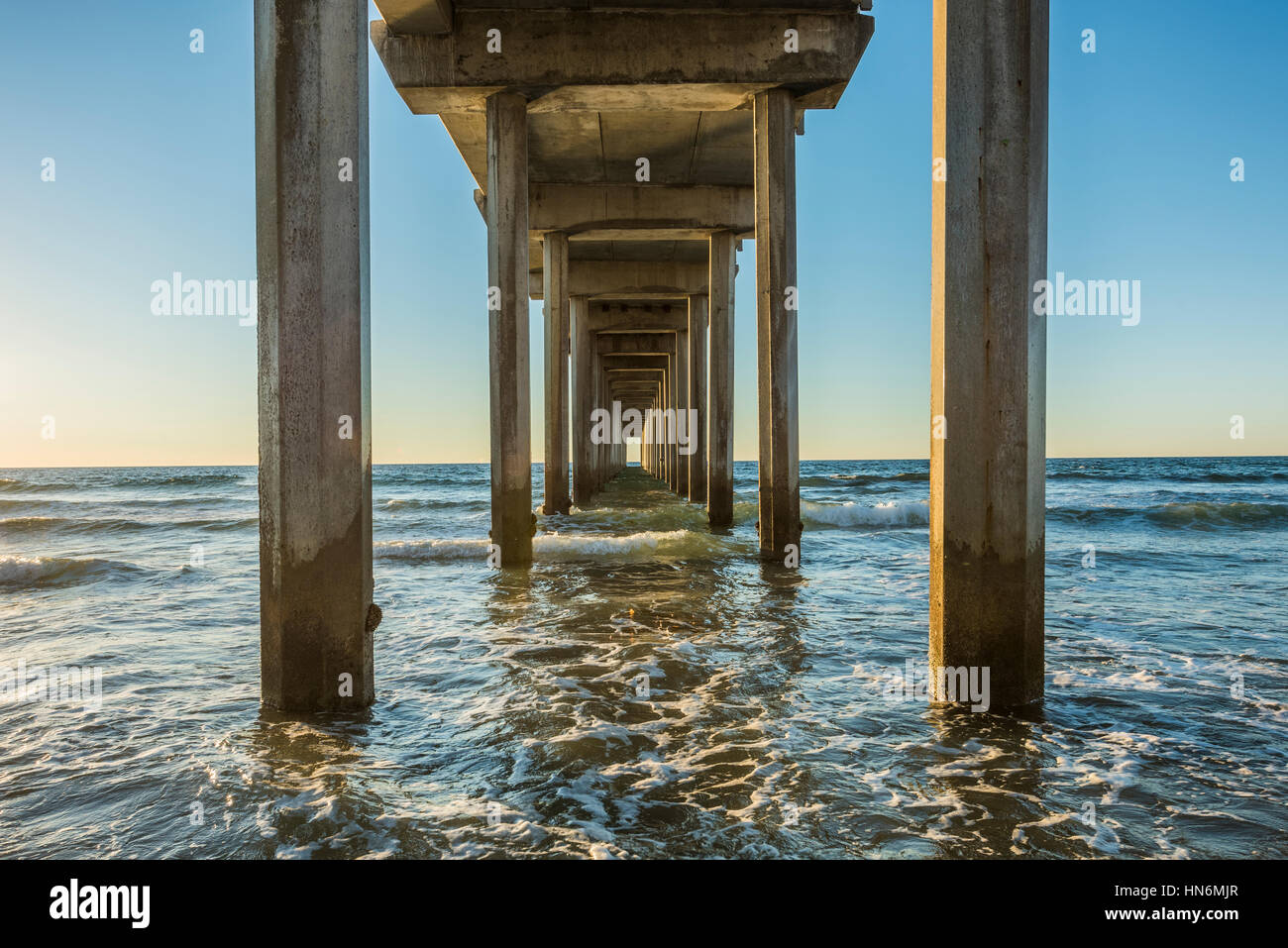 Inquadratura simmetrica sotto Scripps Pier con onde durante il tramonto a La Jolla, San Diego, California Foto Stock