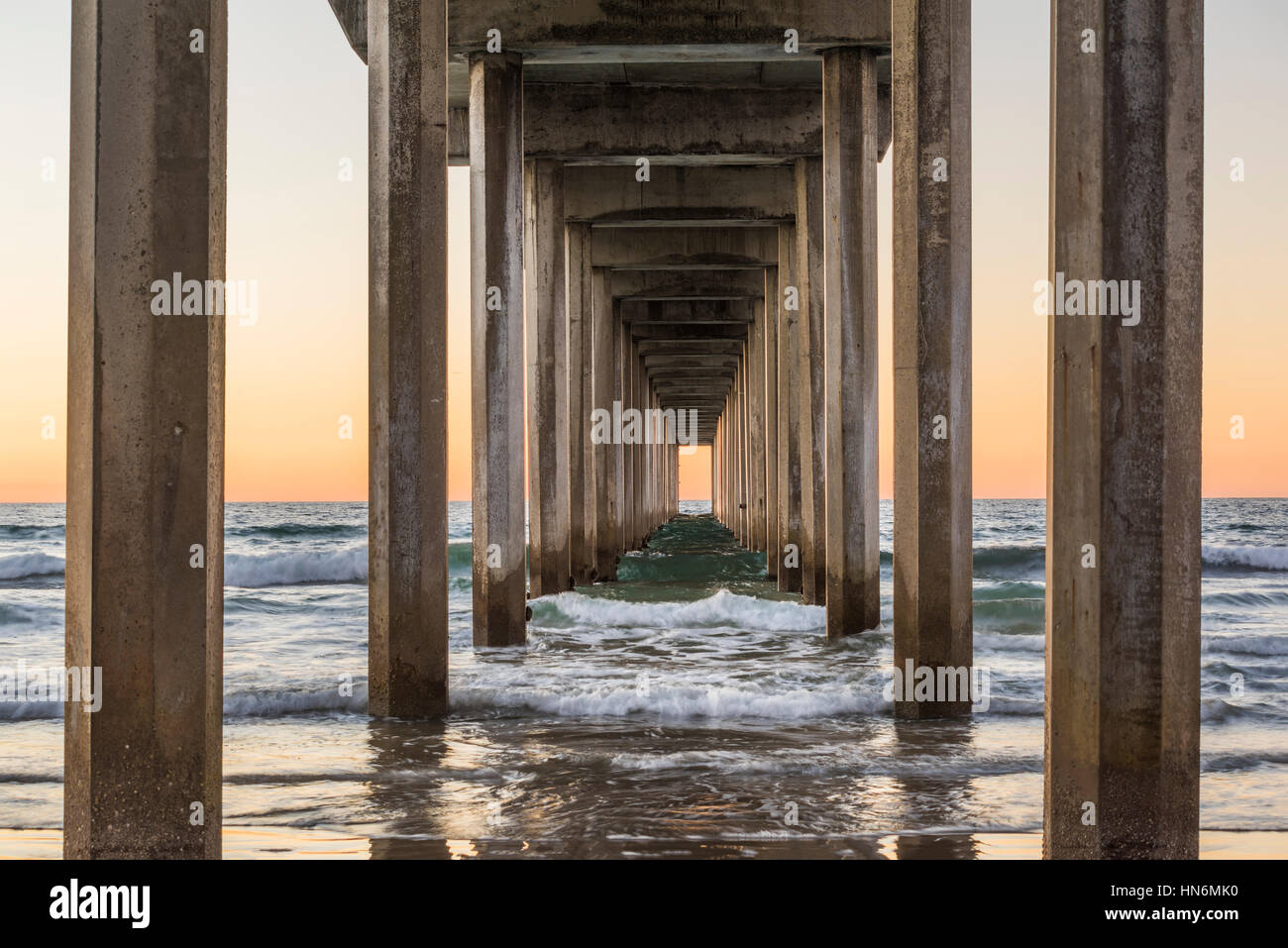 Inquadratura simmetrica sotto Scripps Pier con onde durante il tramonto a La Jolla, San Diego, California Foto Stock