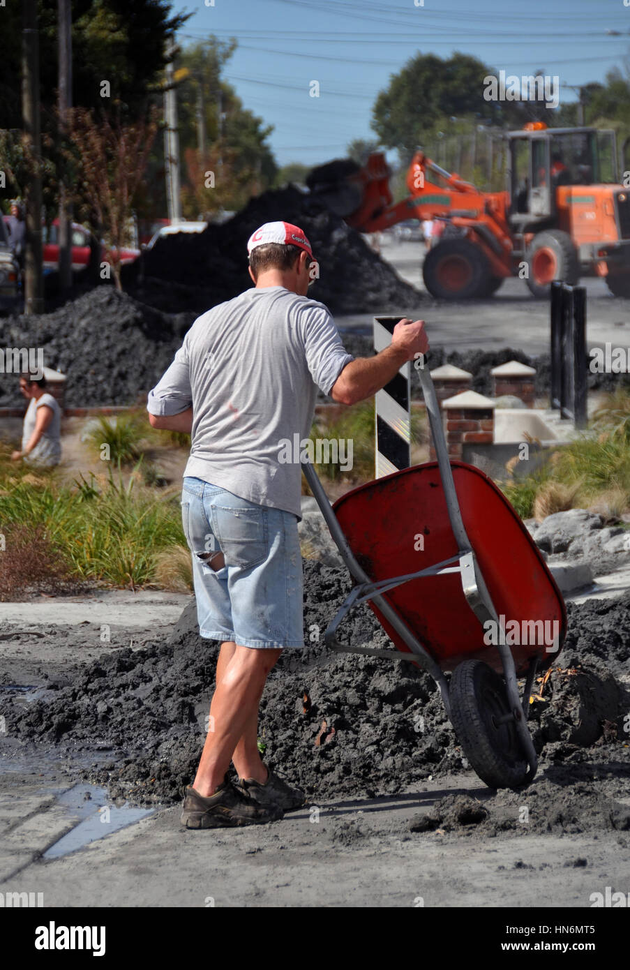 L'uomo cancella la liquefazione dalla sua proprietà dopo il grande terremoto a Christchurch, Nuova Zelanda Foto Stock