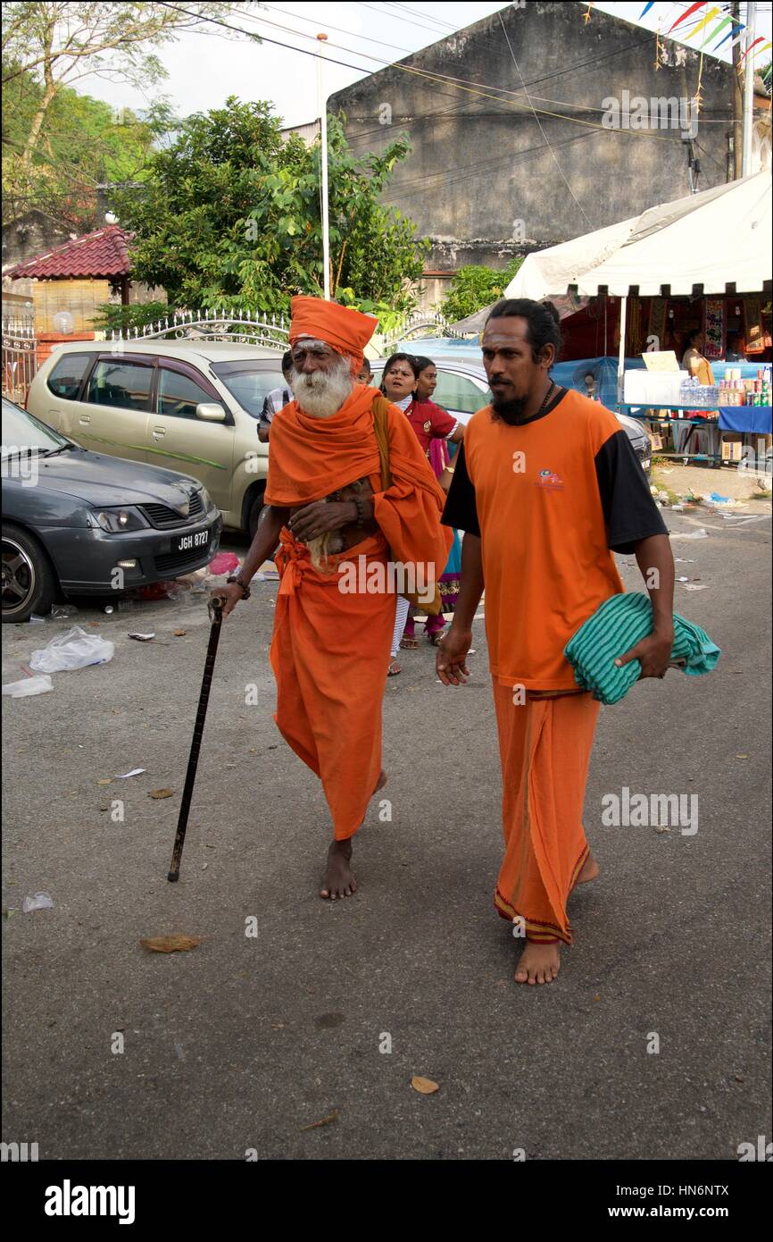 Un senior swami a piedi mentre viene accompagnata da un assistente durante la celebrazione Thaipusam in Penang. Foto Stock