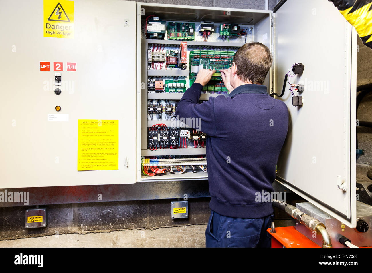 Un elettricista che lavora su un quadro di comando elettronico situato in una scatola di comando Foto Stock
