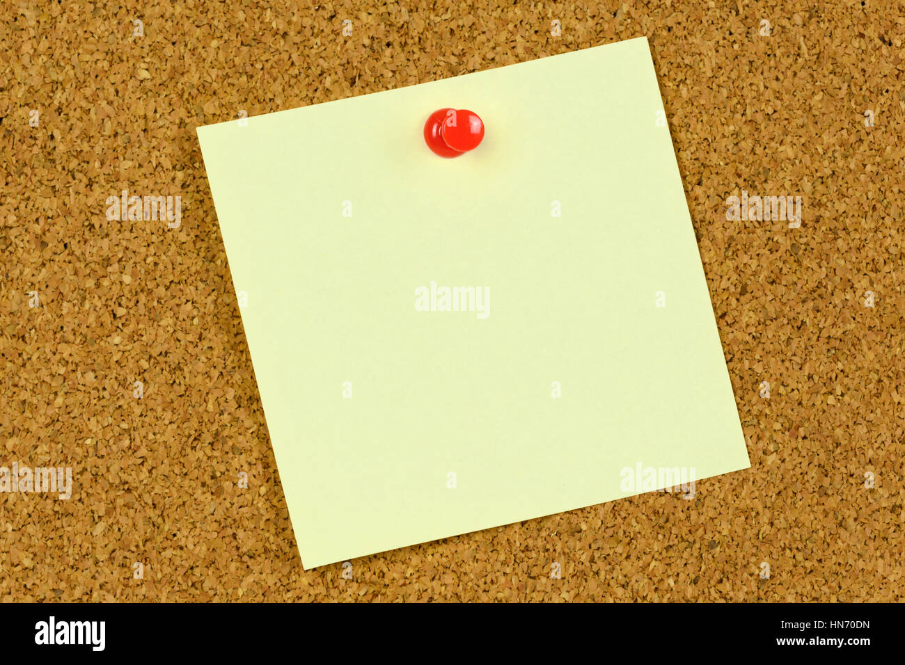 Blank bigliettino giallo tenuto su un tappo di sughero bacheca con una puntina rossa. Foto Stock